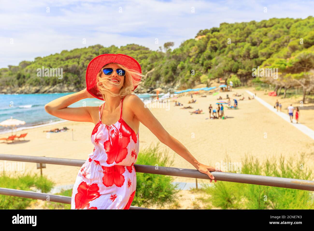 Felice donna turistica con ampio cappello rosso sul tetto a Fetovaia Beach, isola d'Elba, Toscana, Italia, Europa Foto Stock
