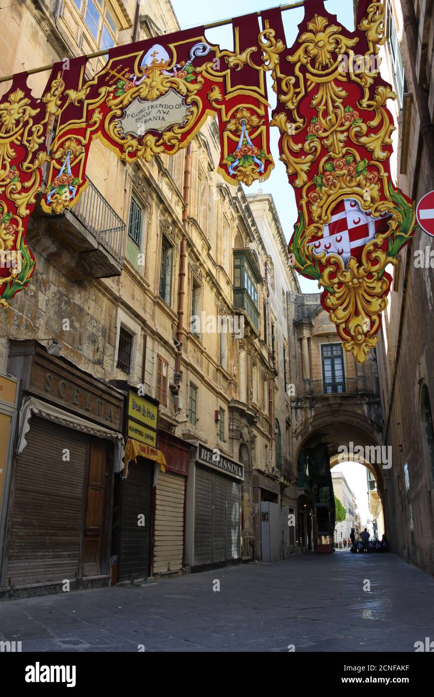 Bandiere religiose rosse e gialle per la Festa di Sant'Agostino appendono dall'altra parte della strada nel centro storico di Valletta, Malta Foto Stock