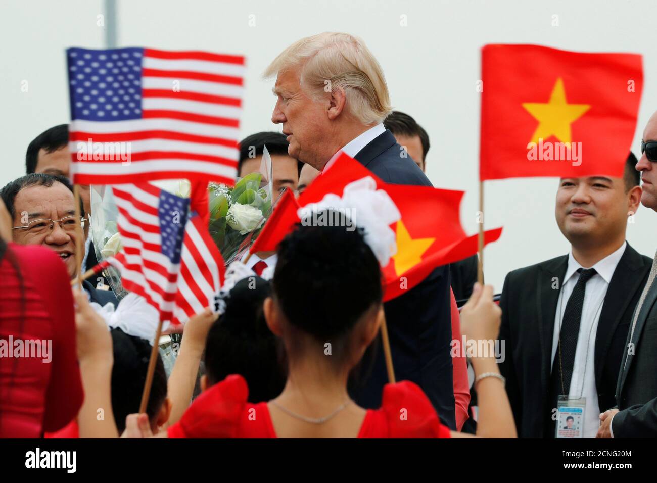 I bambini con bandiere salutano e il presidente degli Stati Uniti Donald Trump salirà a bordo dell'Air Force 1 per partire per le Filippine dall'aeroporto internazionale noi Bai di Hanoi, Vietnam, 12 novembre 2017. REUTERS/Jonathan Ernst Foto Stock