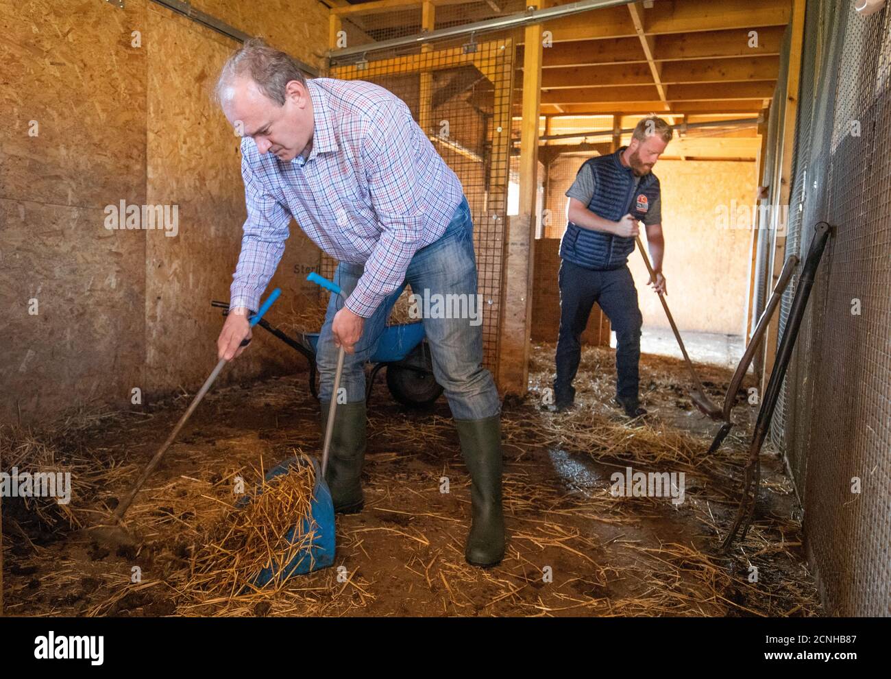 Il leader liberal-democratico ed Davey aiuta il direttore dello zoo Michael Knight (a destra) a pulire le scuderie zebra durante una visita allo zoo di Fife a Cupar per incontrare i proprietari di affari e il personale per scoprire come Covid ha influenzato la loro attività. Foto Stock