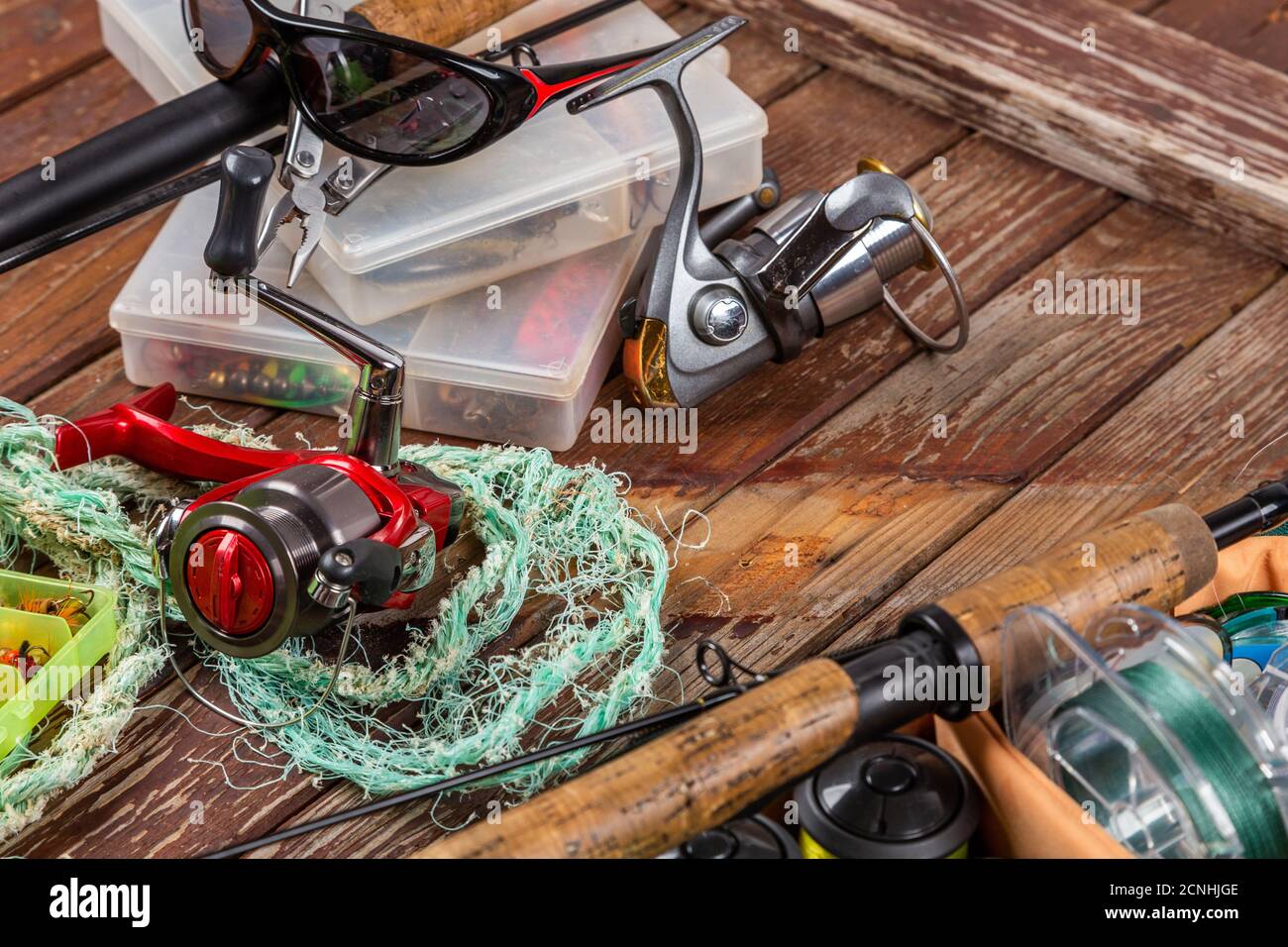 Diverse tegole da pesca con verga e bobine su sfondo marrone di legno. Mockap per la pubblicità e la pubblicazione. Foto Stock