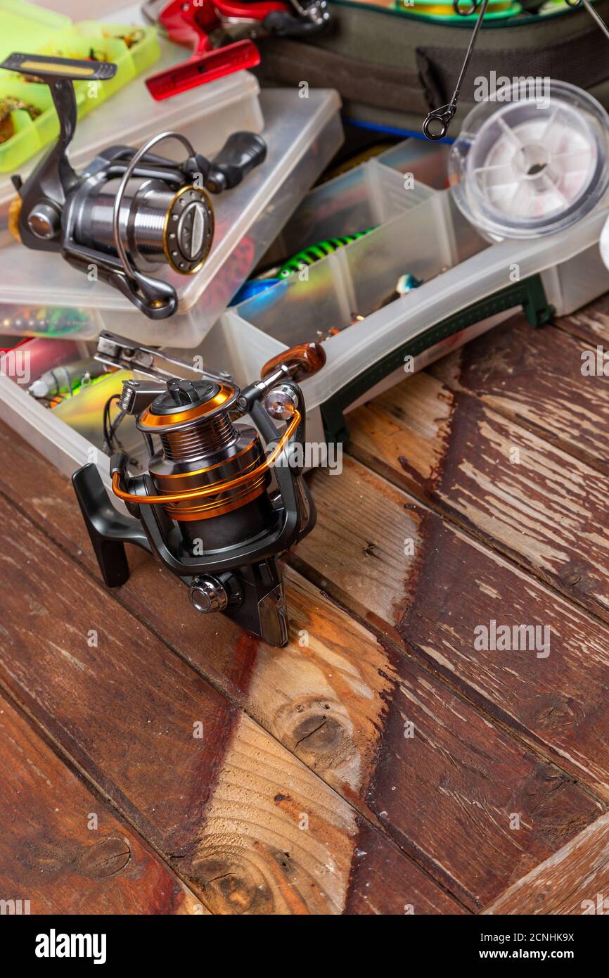 Diverse tegole da pesca con verga e bobine su sfondo marrone di legno. Mockap per la pubblicità e la pubblicazione. Foto Stock
