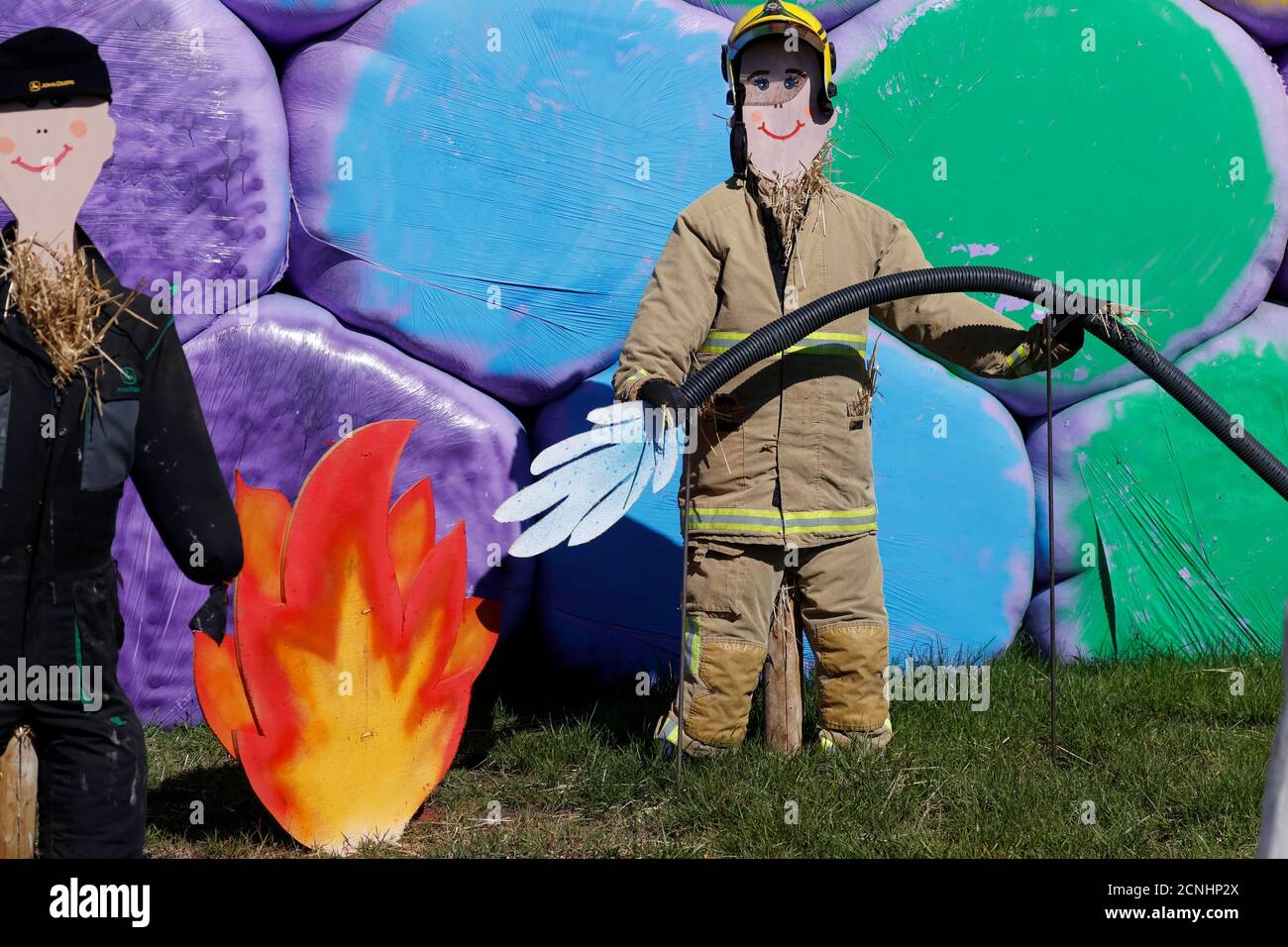 Uno spaventapasseri vestito da pompiere è visto di fronte a balle di fieno arcobaleno colorate in un'azienda agricola a Billinge a seguito dell'epidemia di coronavirus (COVID-19), Billinge, Gran Bretagna, 6 maggio 2020. REUTERS/Phil Noble Foto Stock