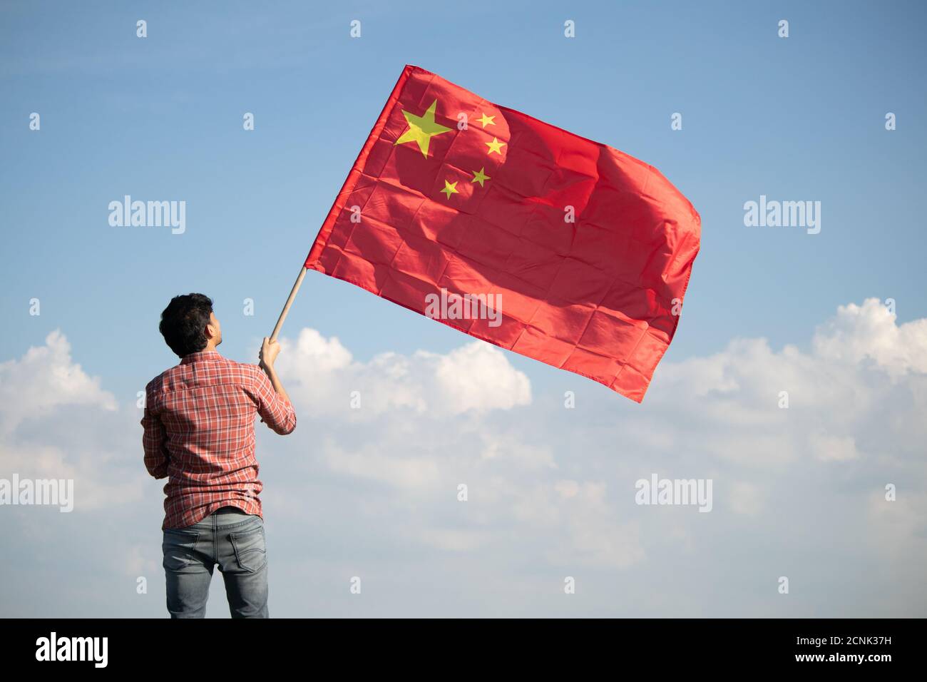 Giovane uomo con orgoglio di tenere sventolante bandiera cinese in cima mountain Peak - concetto che mostra Celebrazione della Repubblica Cinese o. Giornata Nazionale Foto Stock