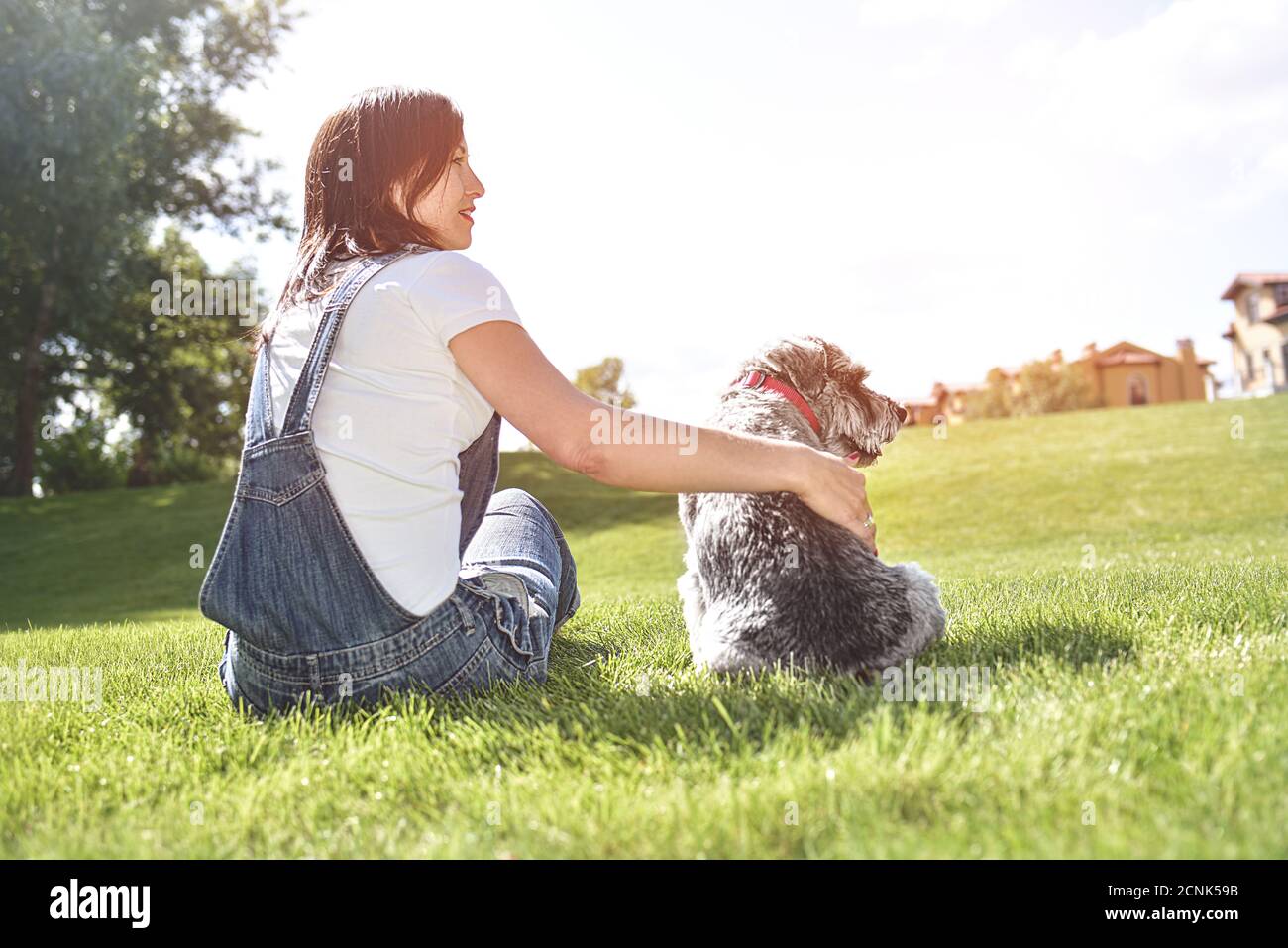 Bella adulta caucasica felice donna che riposa nel parco in una giornata di sole con il suo amato cane. Felice caucasica donna abbracca suo belov Foto Stock