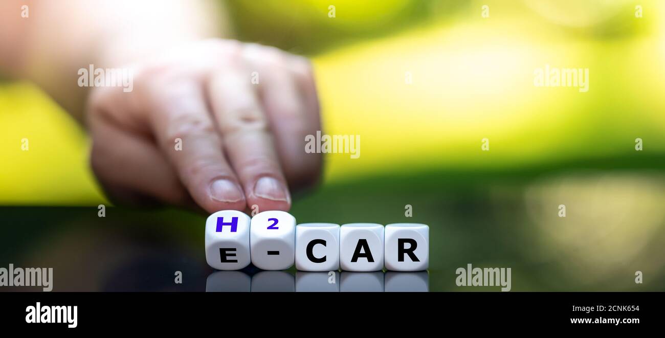 Auto elettrica o a idrogeno? La mano gira i dadi e cambia l'espressione 'e-car' in 'h2 car'. Foto Stock