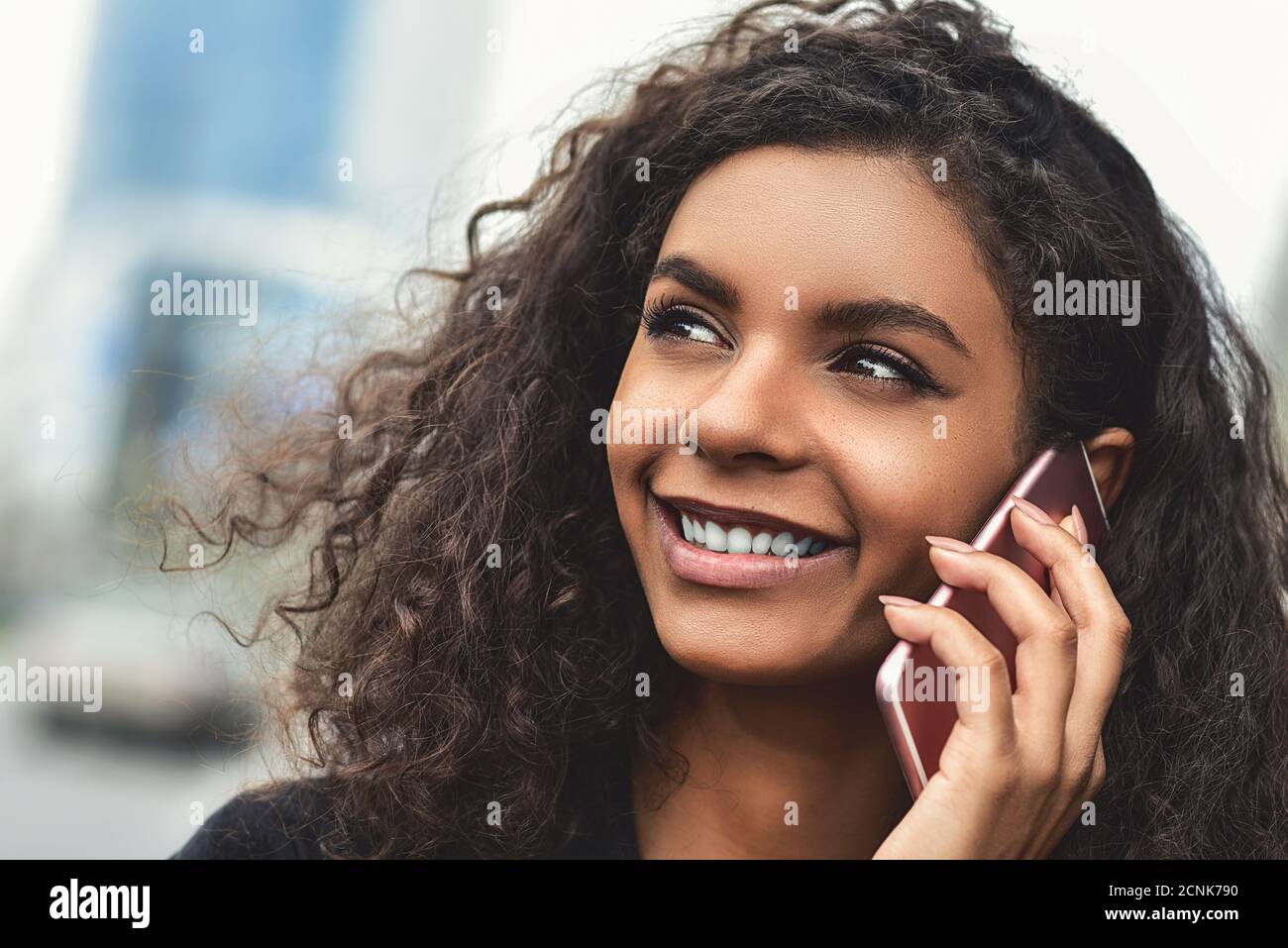 Emozioni positive. Concetto di stile di vita. Primo piano di una giovane donna di razza mista utilizzare un telefono. Foto Stock