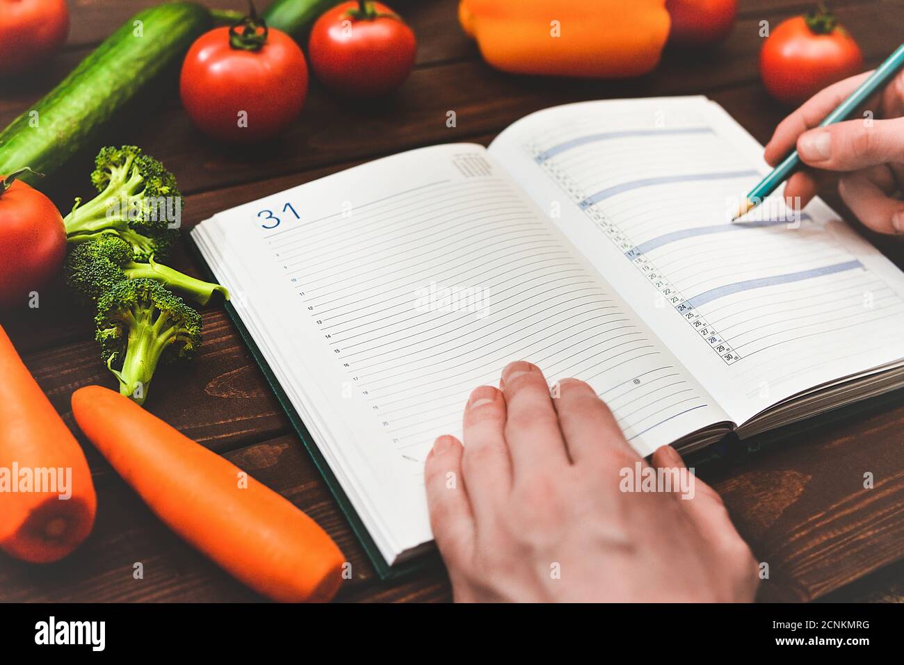 Concetto di dieta con un blocco note e penna circondato da un sacco di verdure fresche sane. Foto Stock