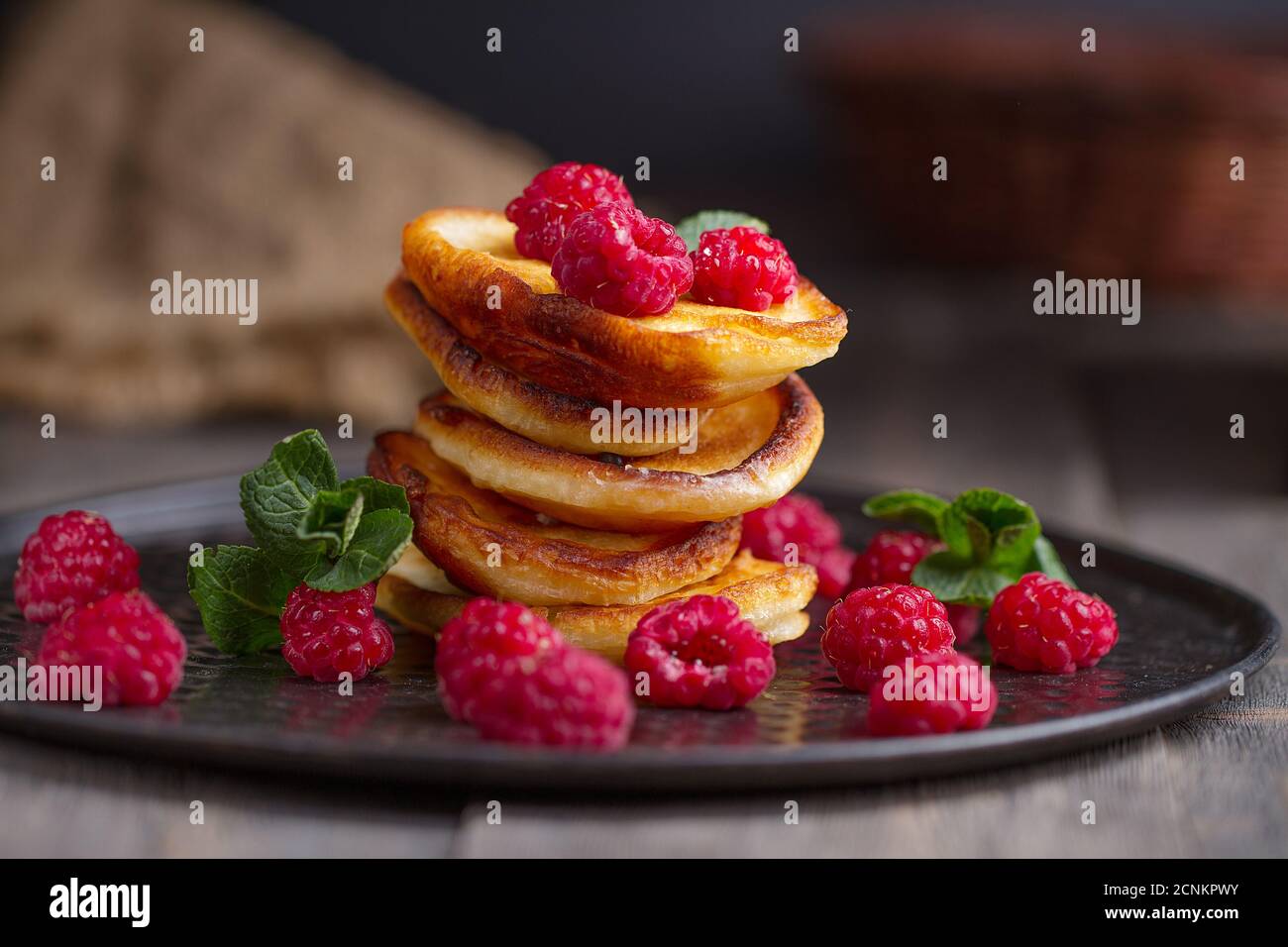 Colazione o brunch fatti in casa: Pancake in stile americano serviti con frutti di bosco e zucchero in polvere su un vecchio tagliere con una tazza di tè nero Foto Stock