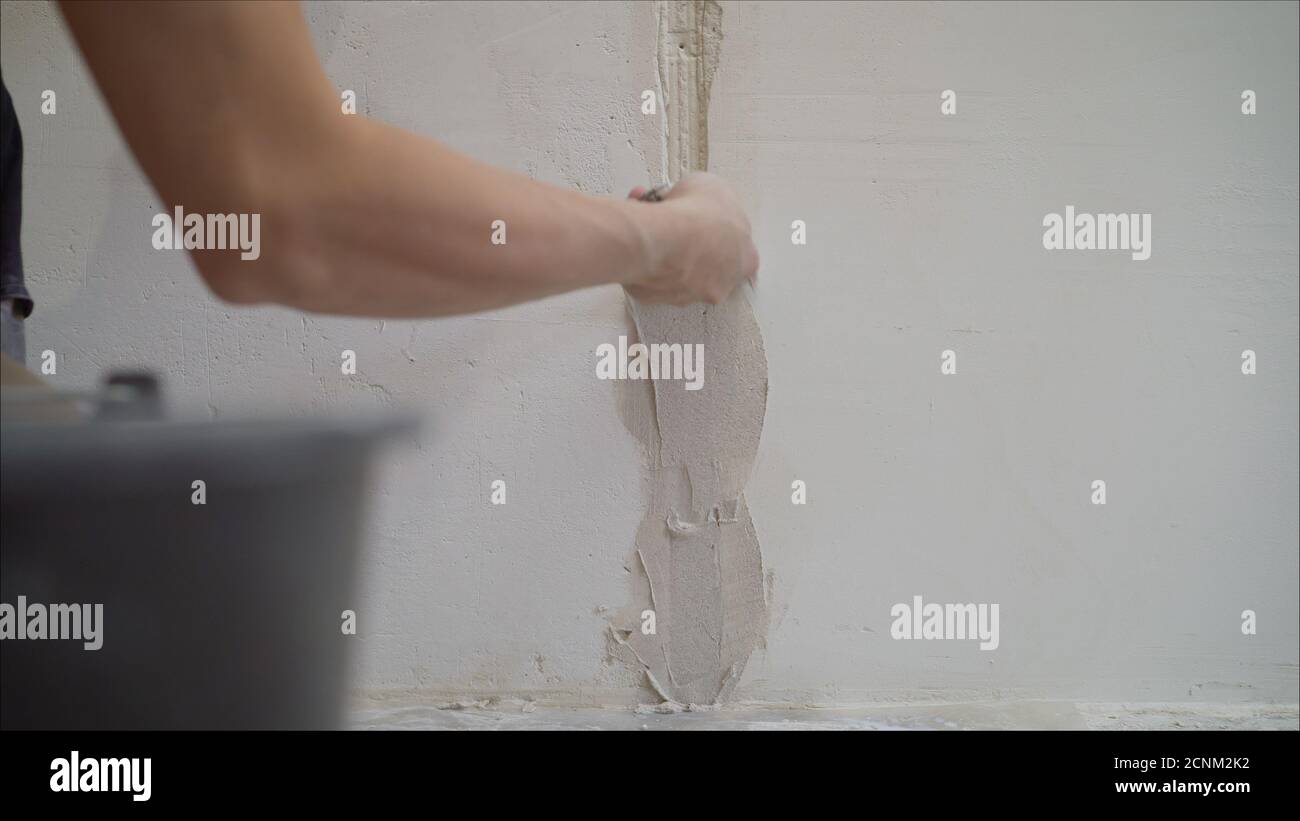 Intonacare il muro. Mani intonacatore al lavoro. Applicazione del gesso sulla parete. Gesso testurizzato Foto Stock