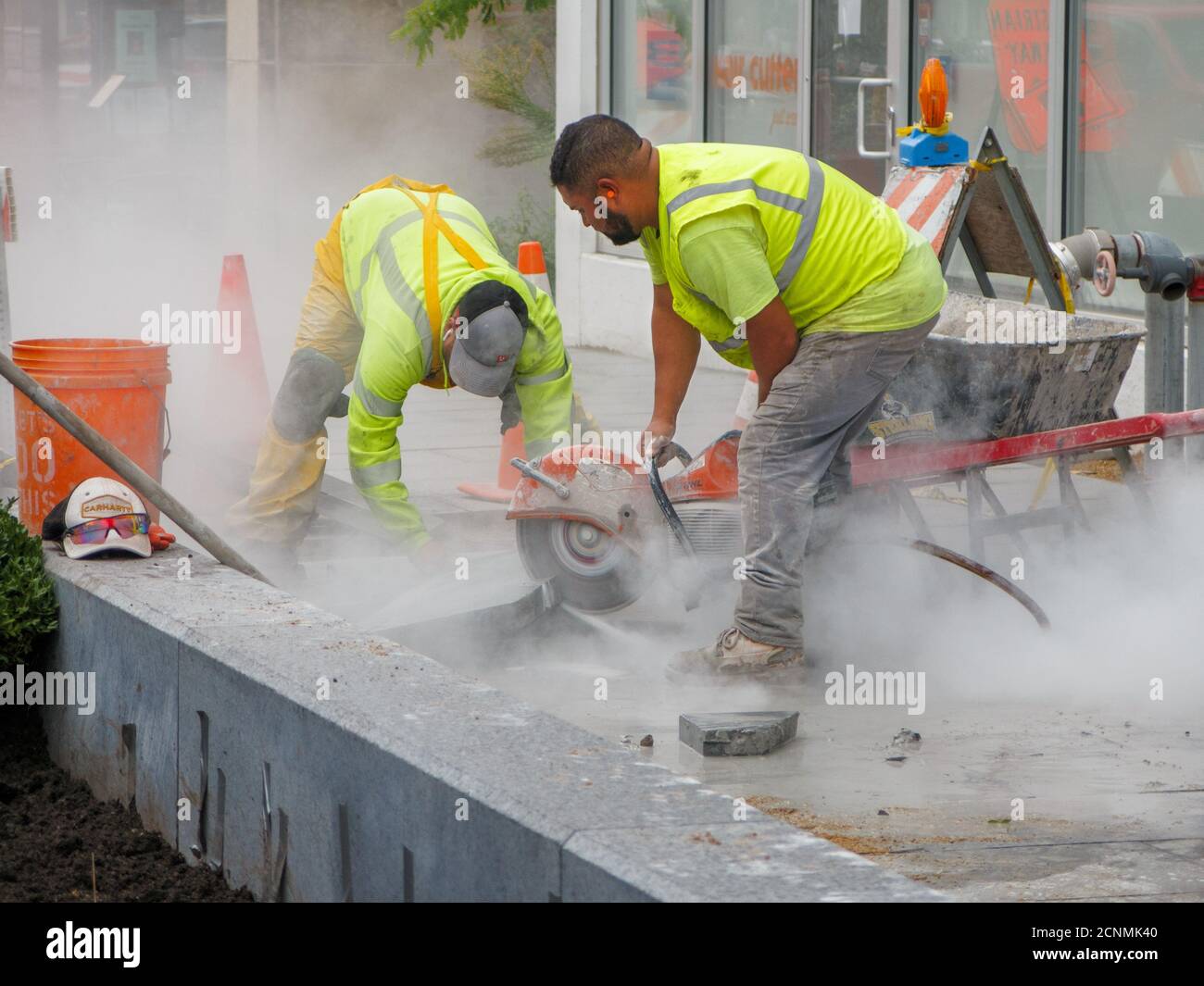 Lavoro con sega circolare raffreddata ad acqua che taglia i blocchi di pavimentazione della pietra. Progetto di ricostruzione di Lake Street. Oak Park, Illinois. Foto Stock