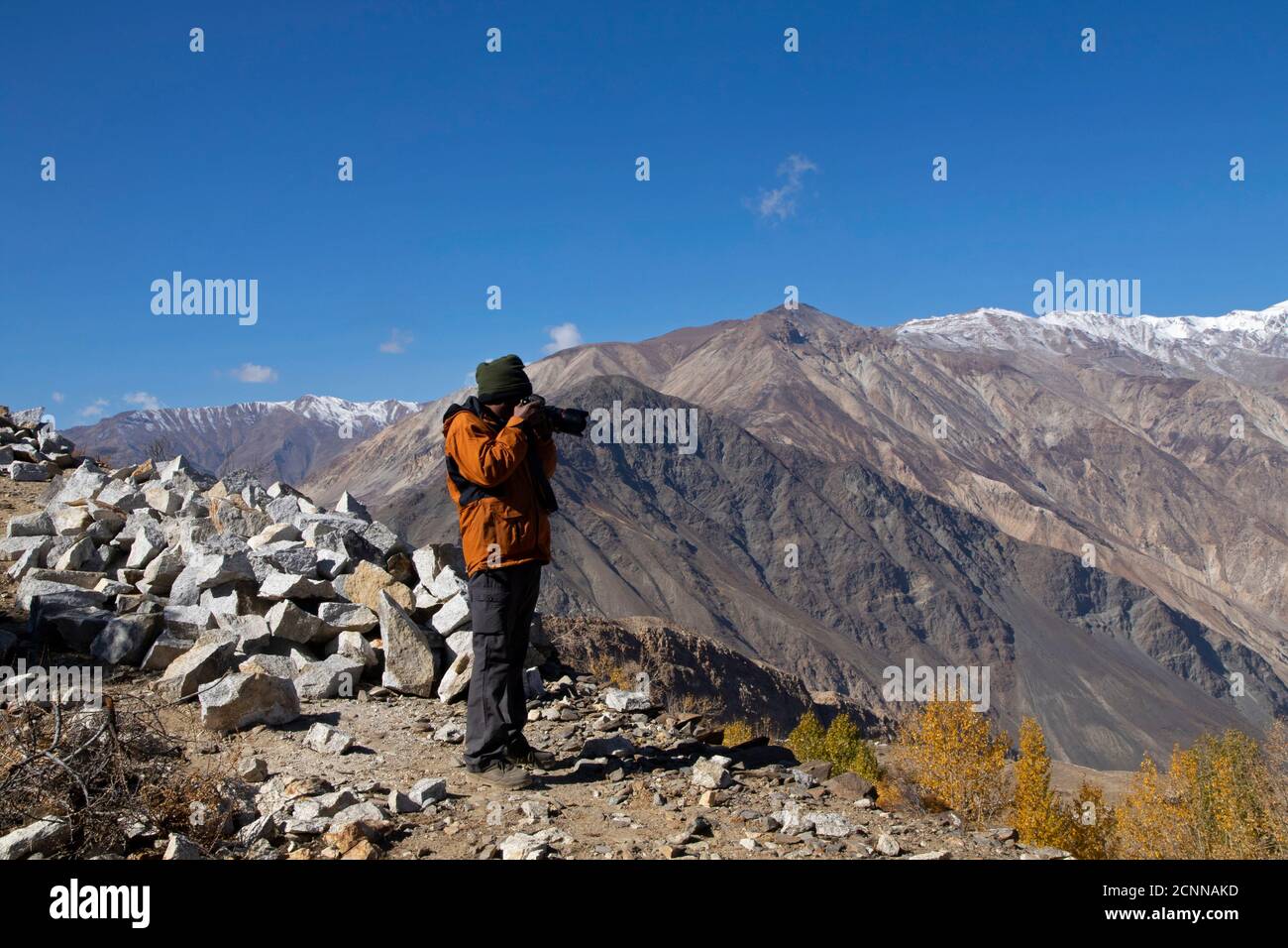 Fotografo e una modella escursione in cima a una collina in una giornata limpida con la luna visibile, il villaggio di Nako, un lago, alberi gialli e montagne textured. Foto Stock