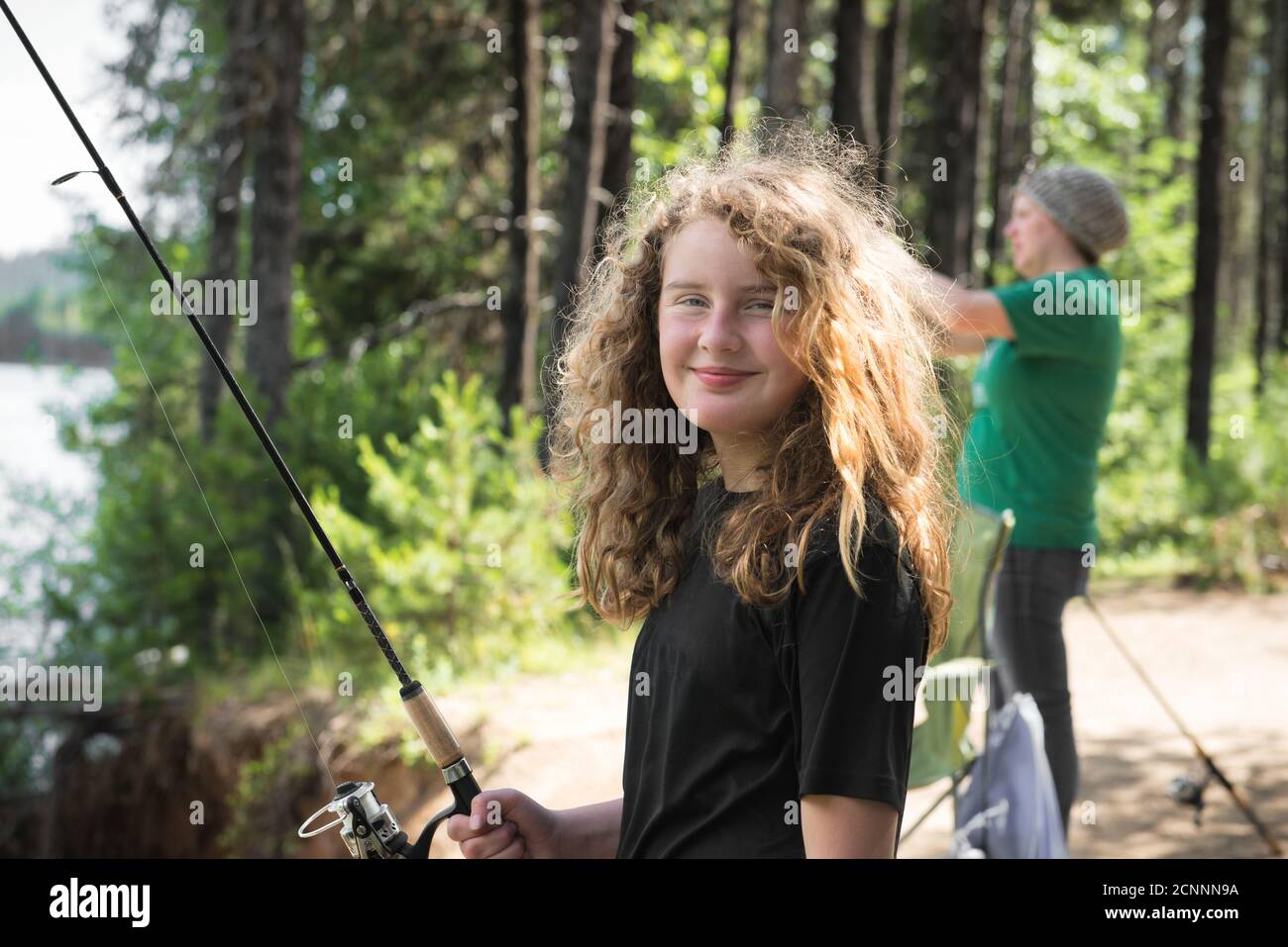 Donna in piedi da un lago di pesca con sua figlia, Oregon, Stati Uniti Foto Stock