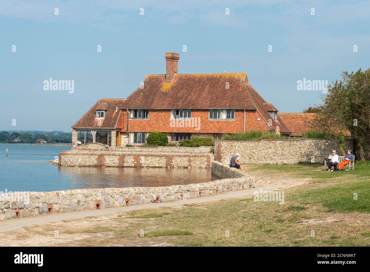 I visitatori si rilassano sul prato che si affaccia su Bosham Quay, un pittoresco villaggio sul mare a West Sussex, Regno Unito Foto Stock