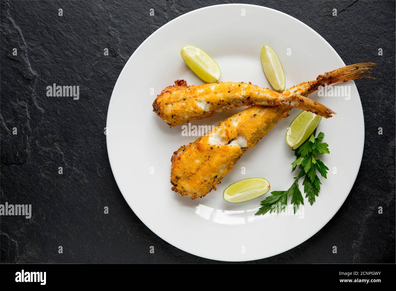 Due gurnard da vasca, Chelidonichthys lucherna, che sono stati skinned, immersi in uova e pane grattugiato e grigliati. Servito con spicchi di lime. Dorset Inghilterra Foto Stock