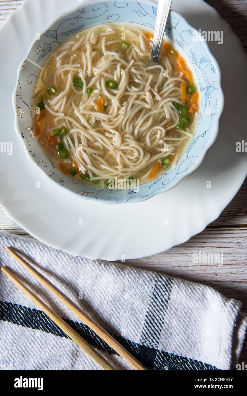 Thukpa, una delicatezza tibetana in una ciotola su un piatto bianco con condimenti su uno sfondo. Foto Stock