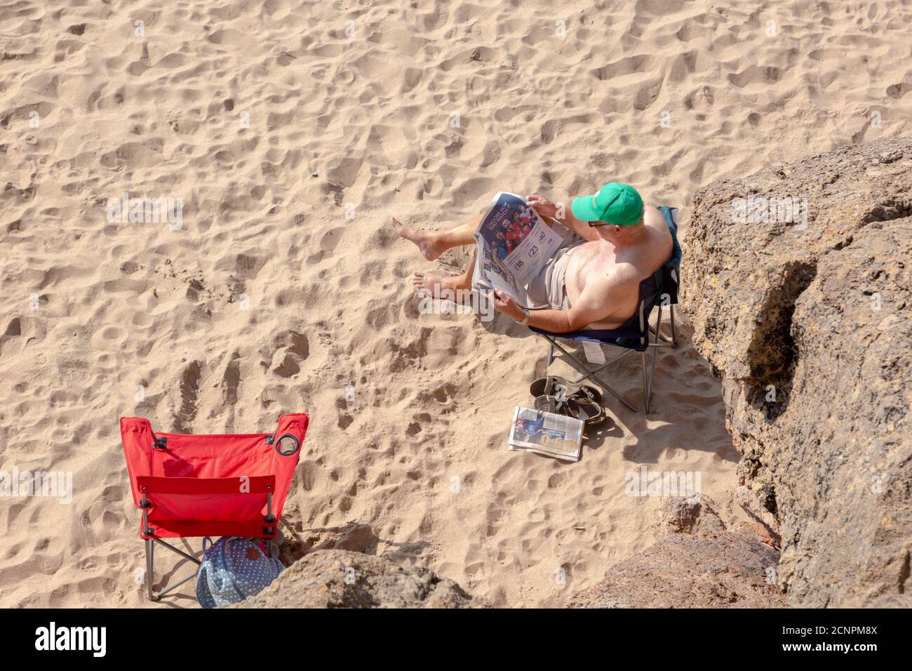 Uomo su una spiaggia britannica che legge un giornale, 2020 Foto Stock