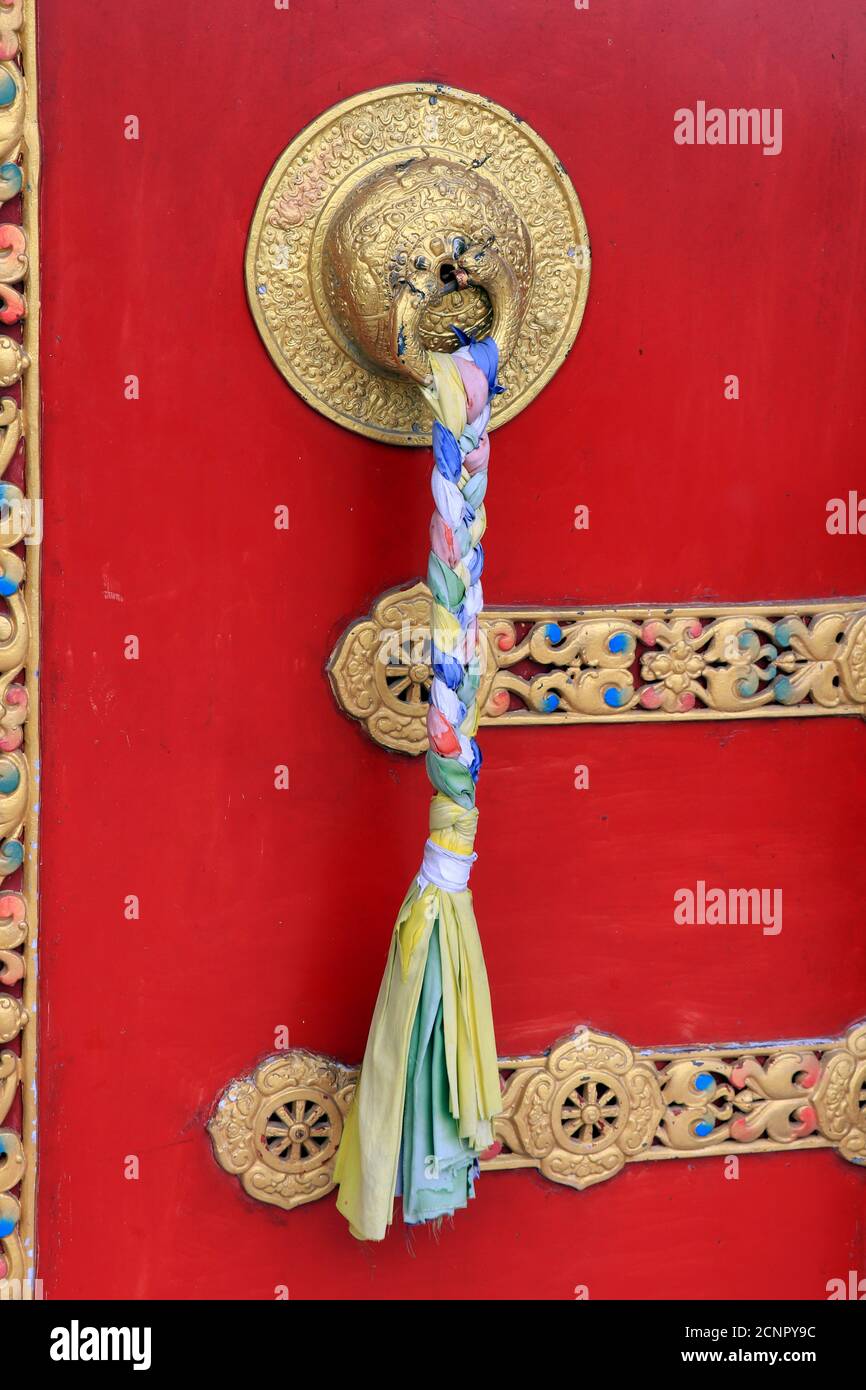 Maniglie ornate e sciarpe di preghiera sull'antico monastero del parco del Buddha a Ravangla nel sud di Sikkim, India. Porta di colore rosso al Parco Buddha di Ravangla. Foto Stock