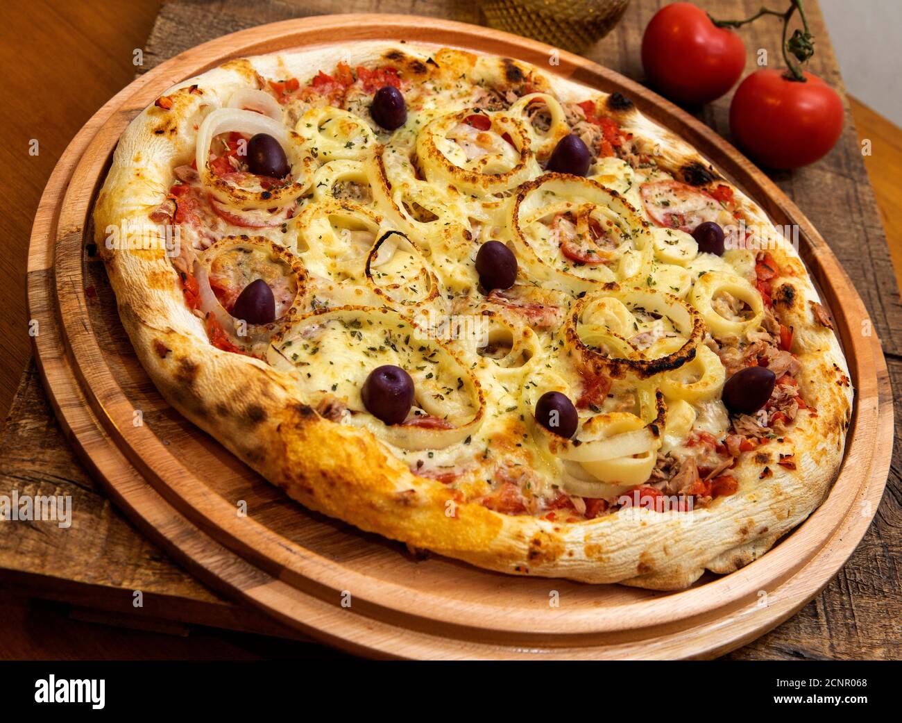 Tonno pizza italiana servita senza taglio su una tavola di legno in una cucina o pizzeria Foto Stock