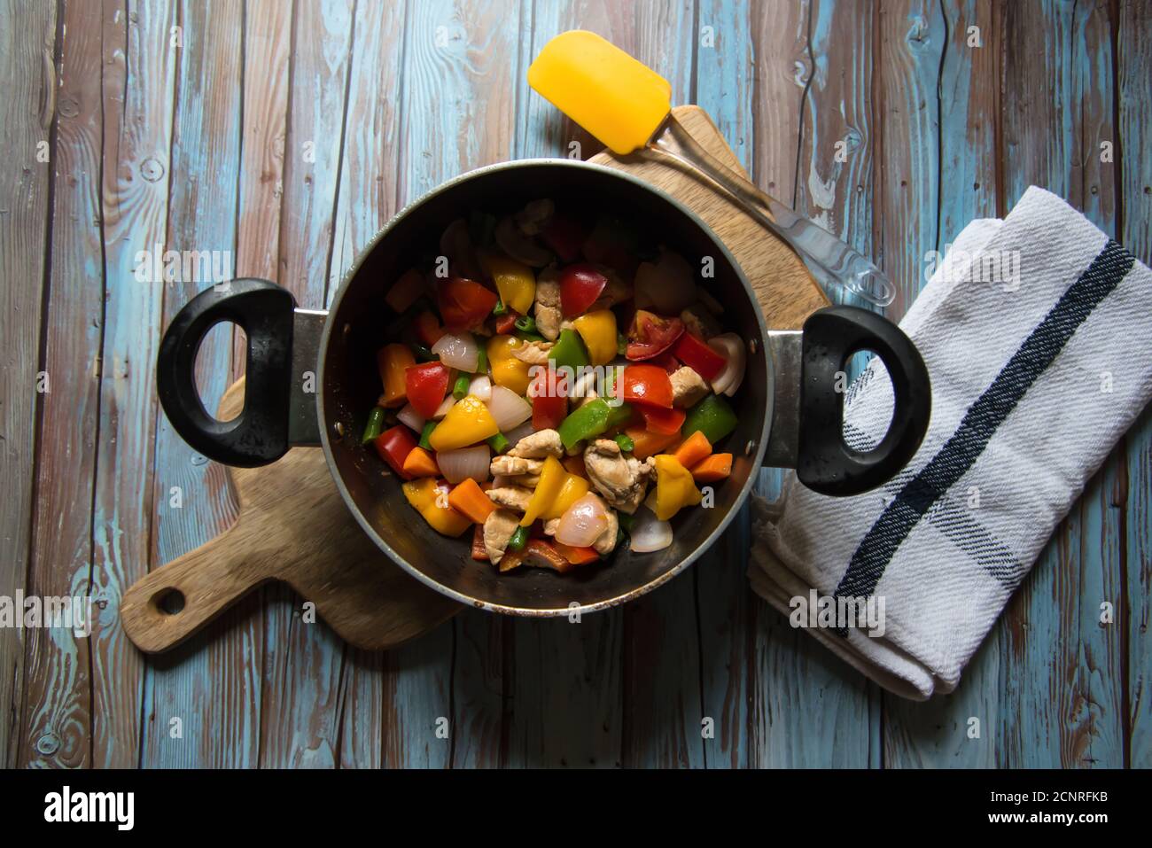 Pollo e verdure bollite saltati in una padella su uno sfondo. Foto Stock