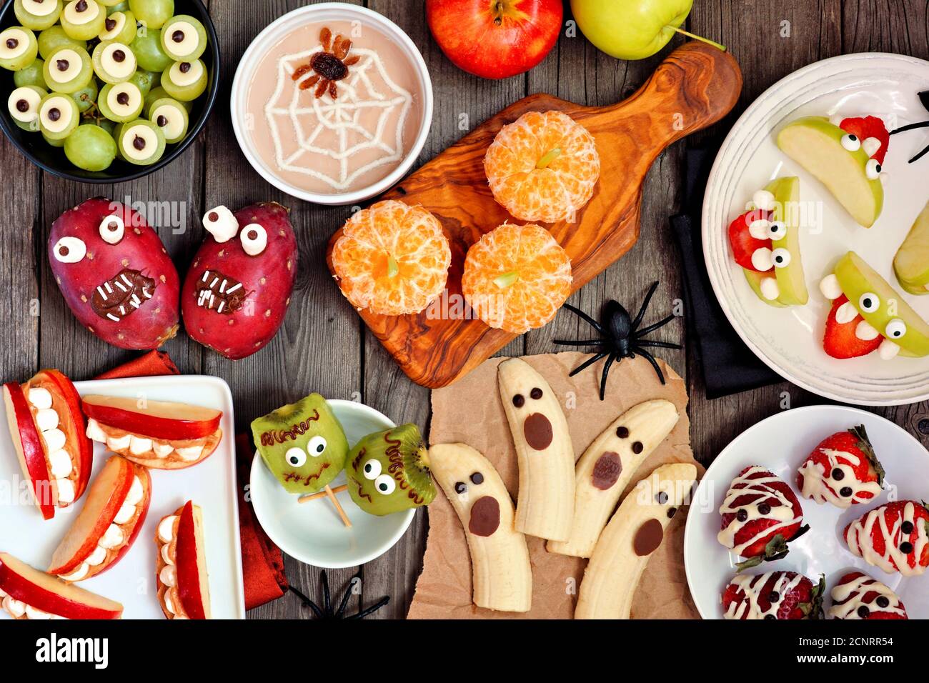 Spuntini sani alla frutta di Halloween. Selezione di divertenti e gustose prelibatezze. Tavolo con vista dall'alto su uno sfondo rustico in legno. Foto Stock