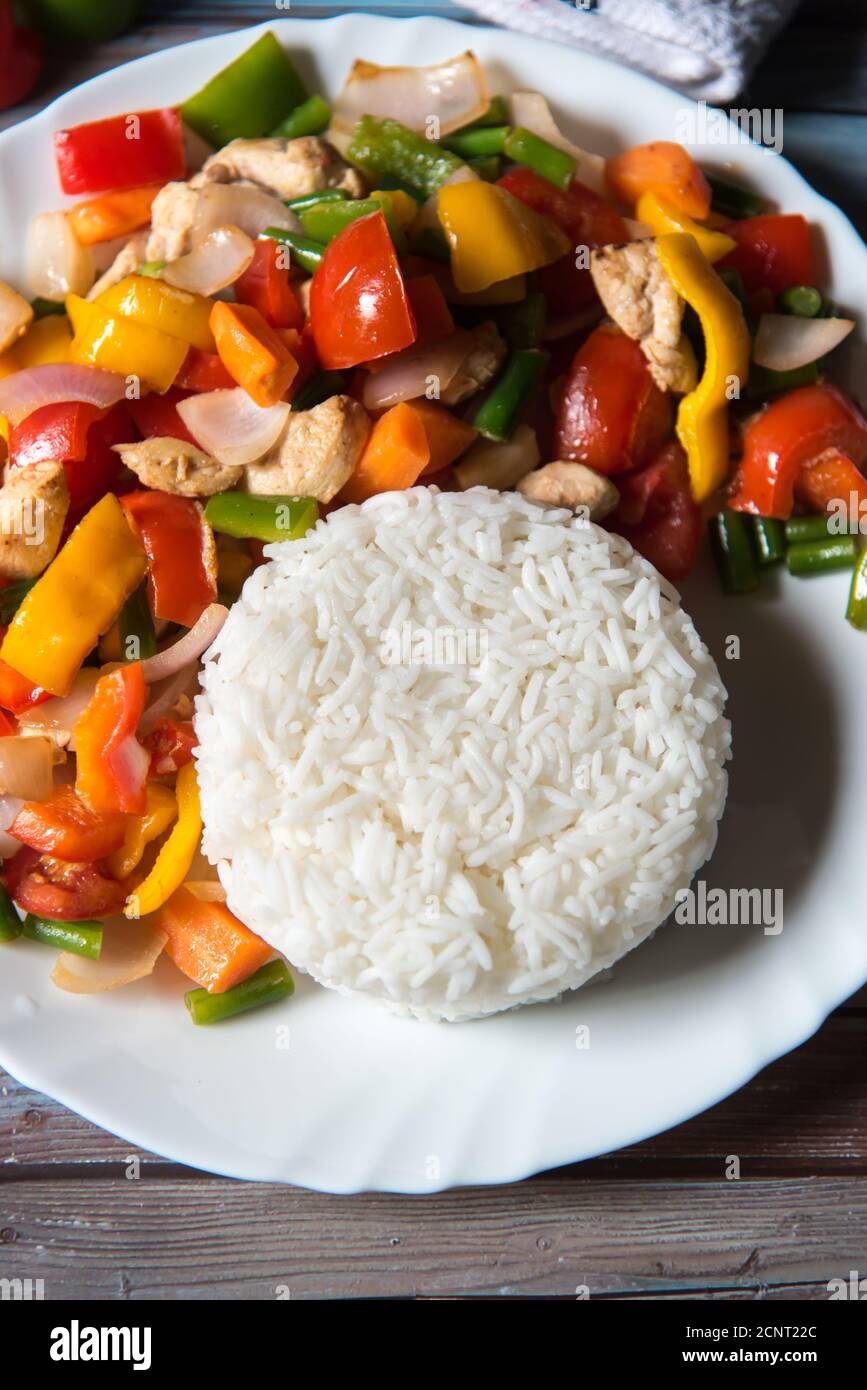 Riso bollito con pollo e verdure saltate in un piatto bianco con  ingredienti su sfondo Foto stock - Alamy