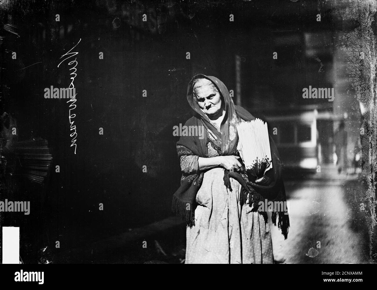 Immagine di una donna anziana che indossa uno scialle e porta giornali  sotto il braccio, camminando su una strada a Chicago, Illinois, circa 1905  Foto stock - Alamy