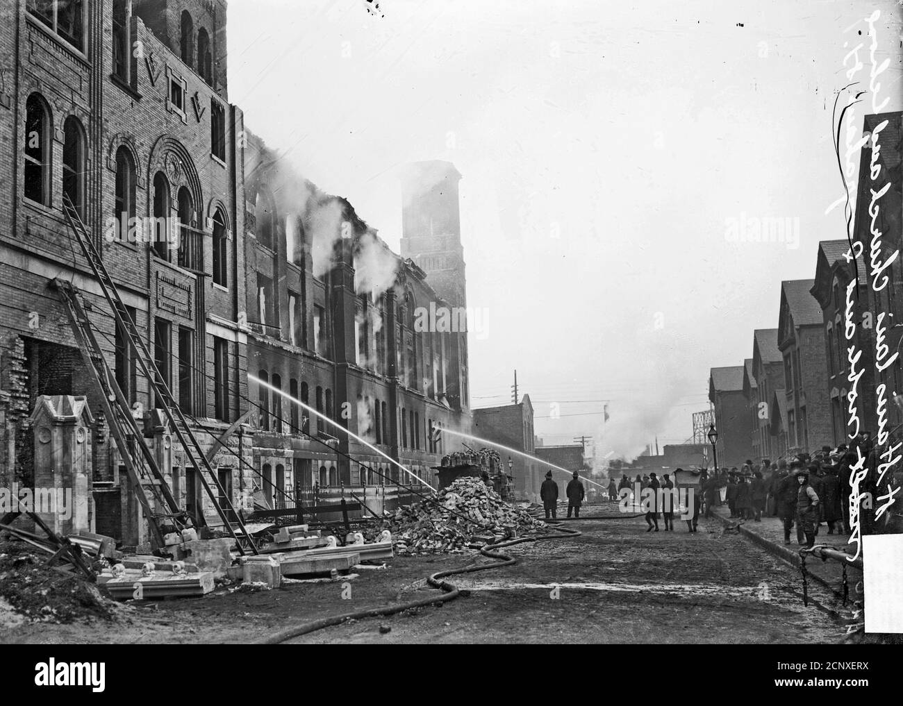 Kostka School spara al 1255 North Noble Street, i vigili del fuoco spruzzano acqua sul lato dell'edificio come una folla di orologi, Chicago, Illinois Foto Stock