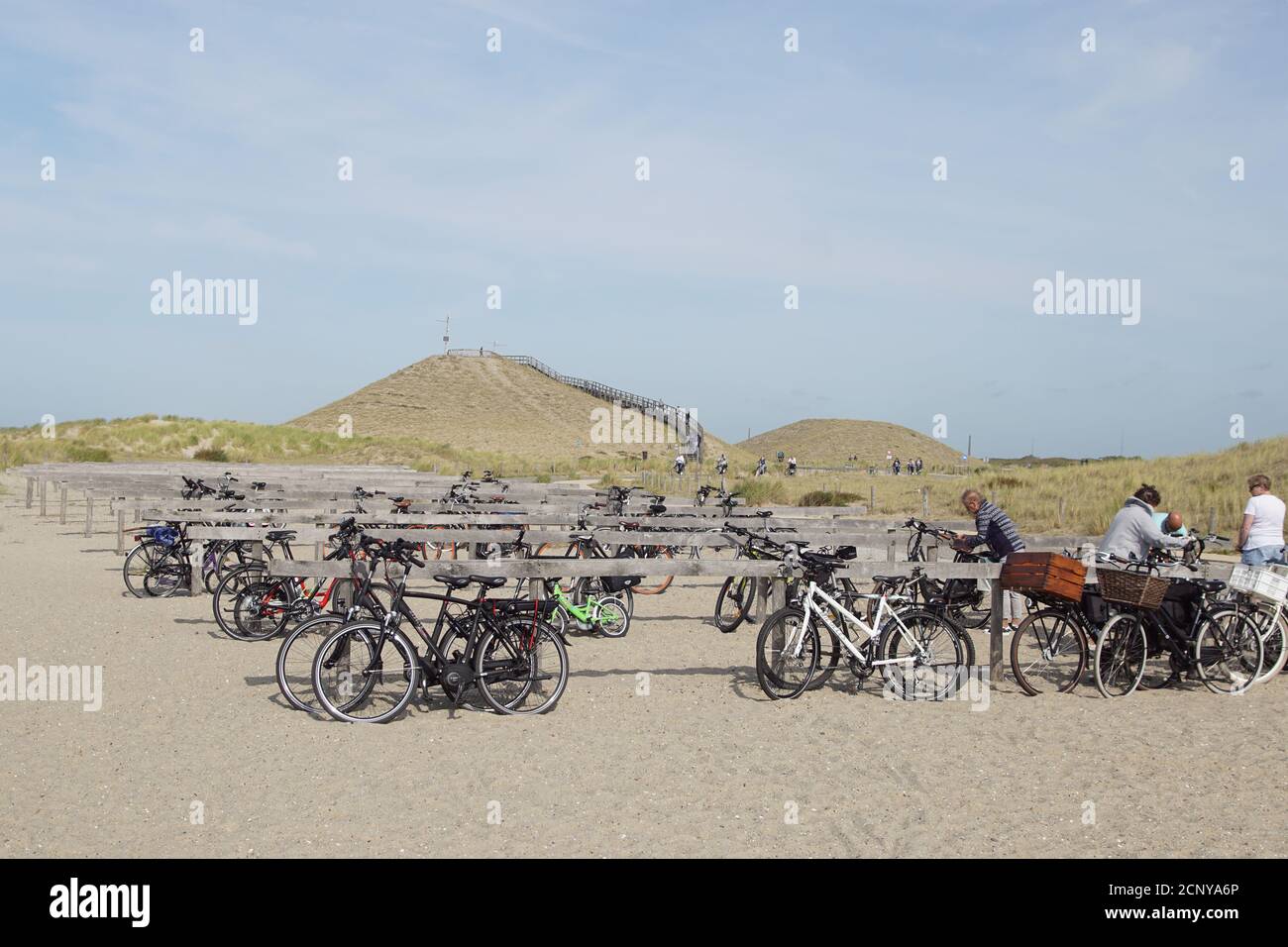 Deposito biciclette, biciclette, in lontananza la duna panoramica alta 26 metri con scale per avere una vista sul Mare del Nord presso il villaggio olandese di Petten. Foto Stock