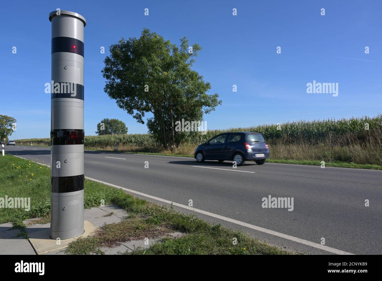Applicazione del limite di velocità stazionaria accanto a una strada e un'auto di passaggio sfocata, monitoraggio del traffico con radar luminoso e telecamera per punire la velocità con pinna Foto Stock