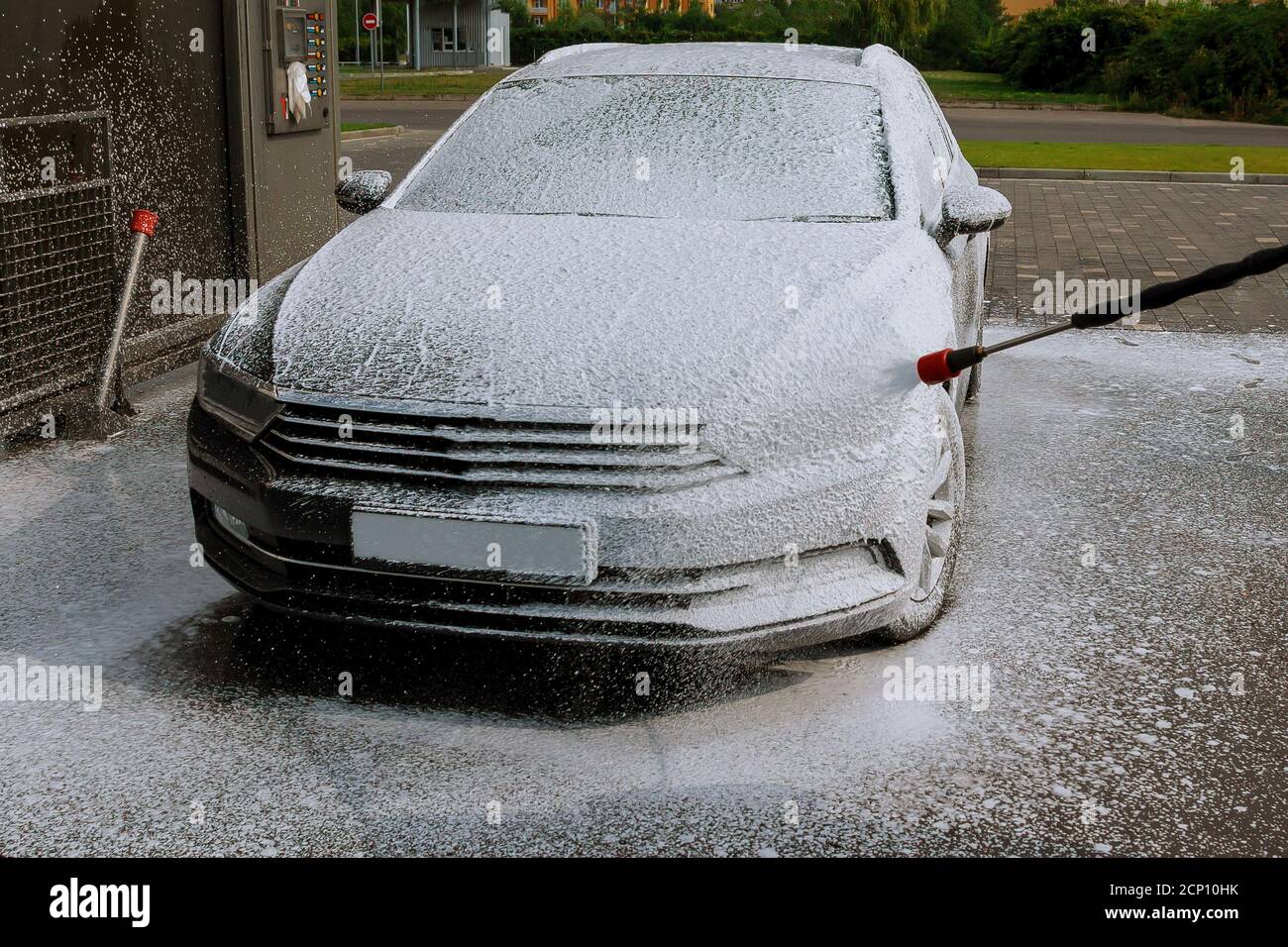 Il proprietario dell'automobile si lava self-service con la schiuma in lavaggi a. autolavaggio self service Foto Stock