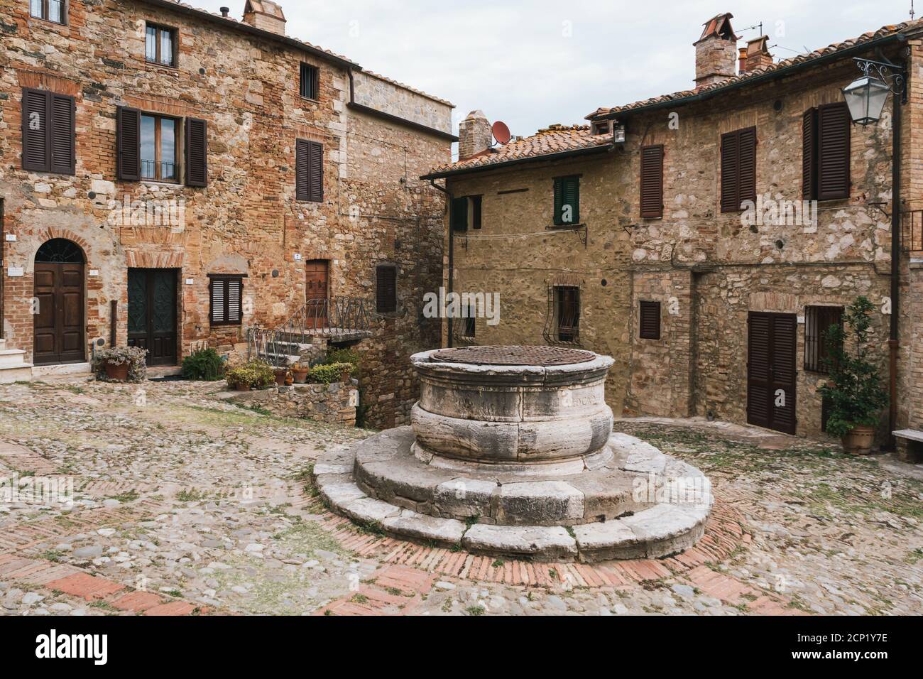 Centro di Castiglione d'Orcia con un pozzo antico e ciottoli in Toscana, Italia e Case di pietra Foto Stock