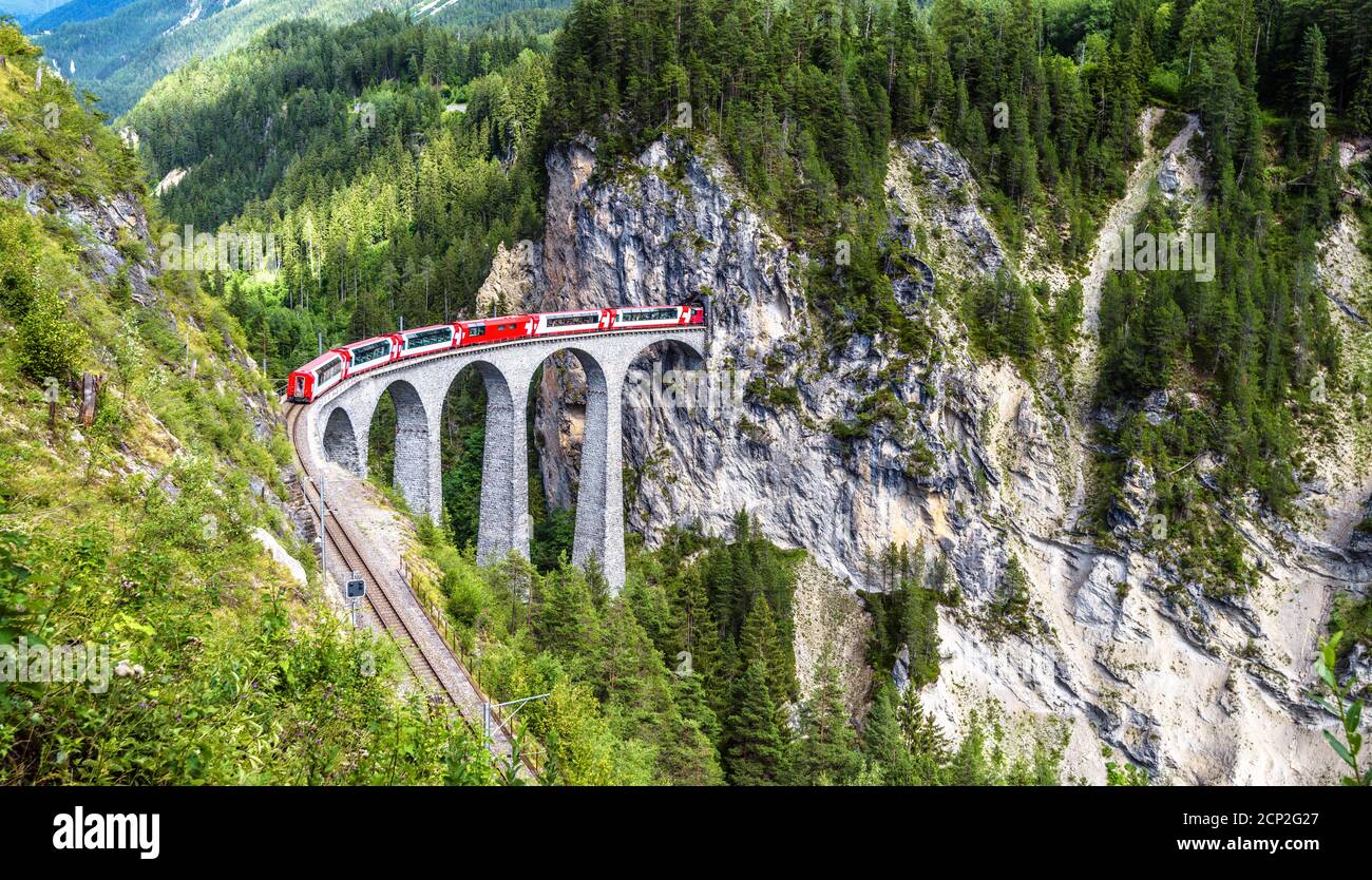 Paesaggio con Viadotto Landwasser in estate, Filisur, Svizzera. E' un punto di riferimento delle Alpi Svizzere. Vista panoramica del ponte ferroviario e del treno rosso. Rhae Foto Stock