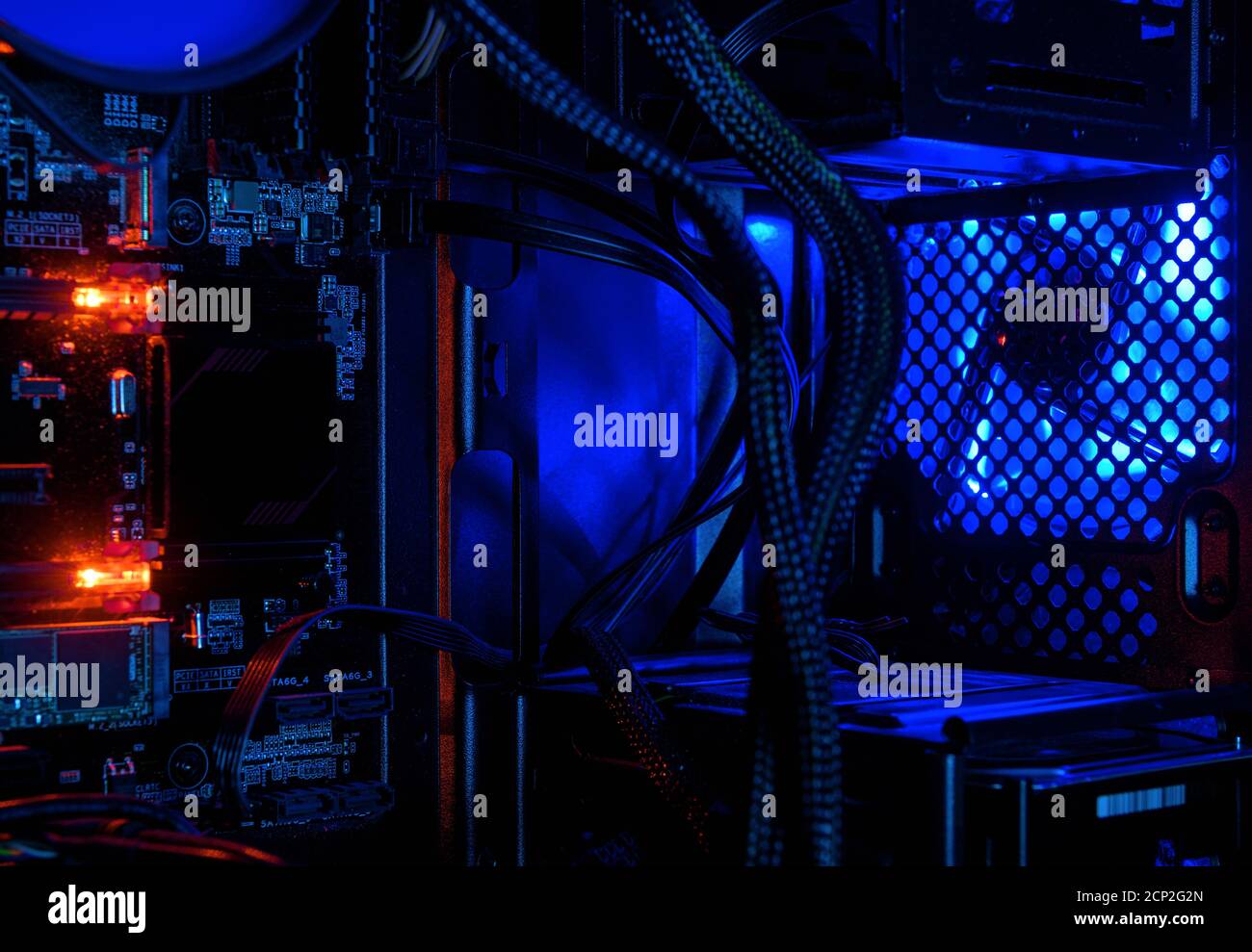 Computer illuminato da luci LED RGB interne, hardware all'interno di un PC desktop aperto ad alte prestazioni. La torre aperta del computer di gioco per lo sfondo. Co Foto Stock