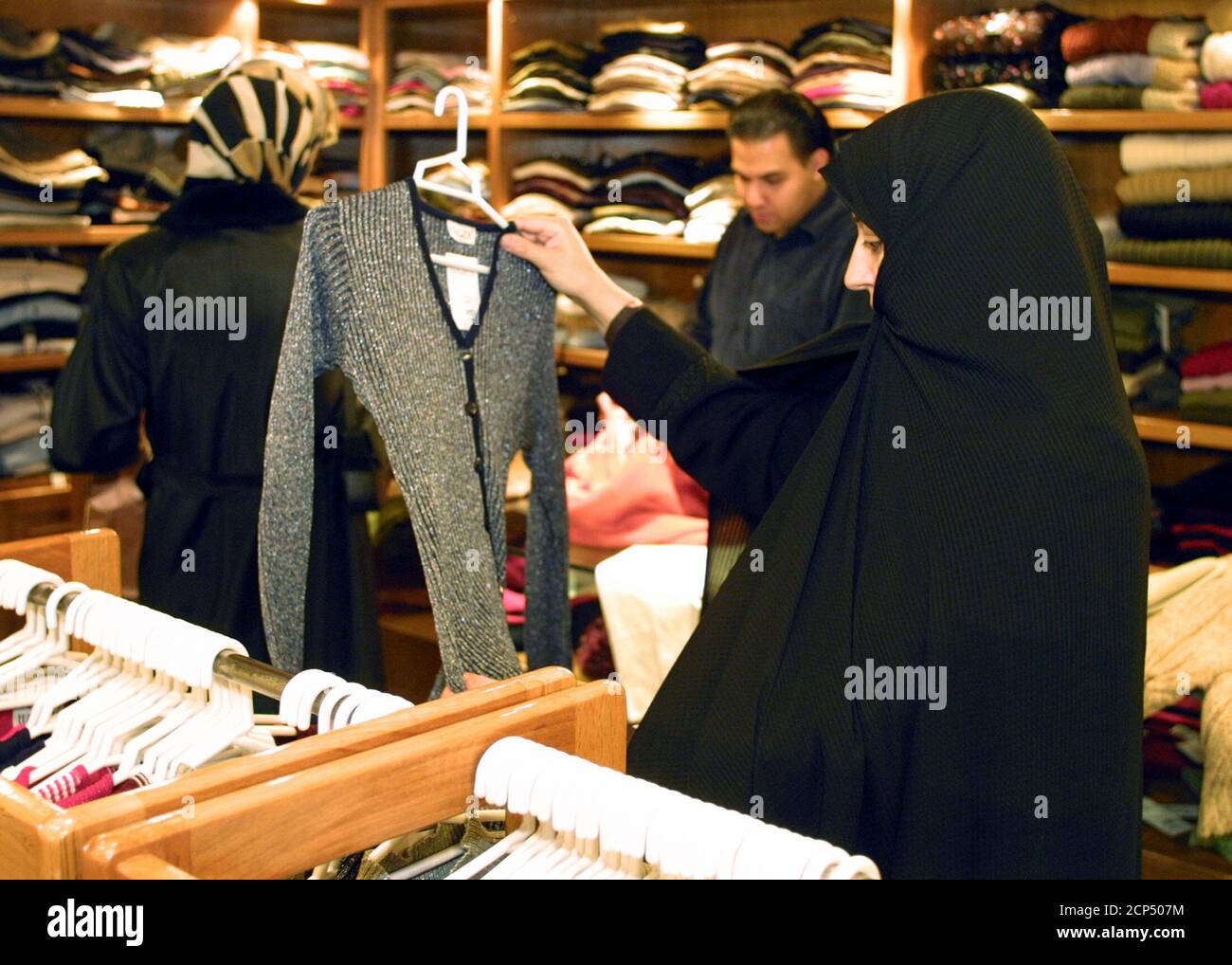 Una donna iraniana che indossa il chador tradizionale guarda un maglione in  un negozio di abbigliamento di lusso nel nord di Teheran 8 novembre 2003.  Dalla rivoluzione islamica nel 1979, le donne
