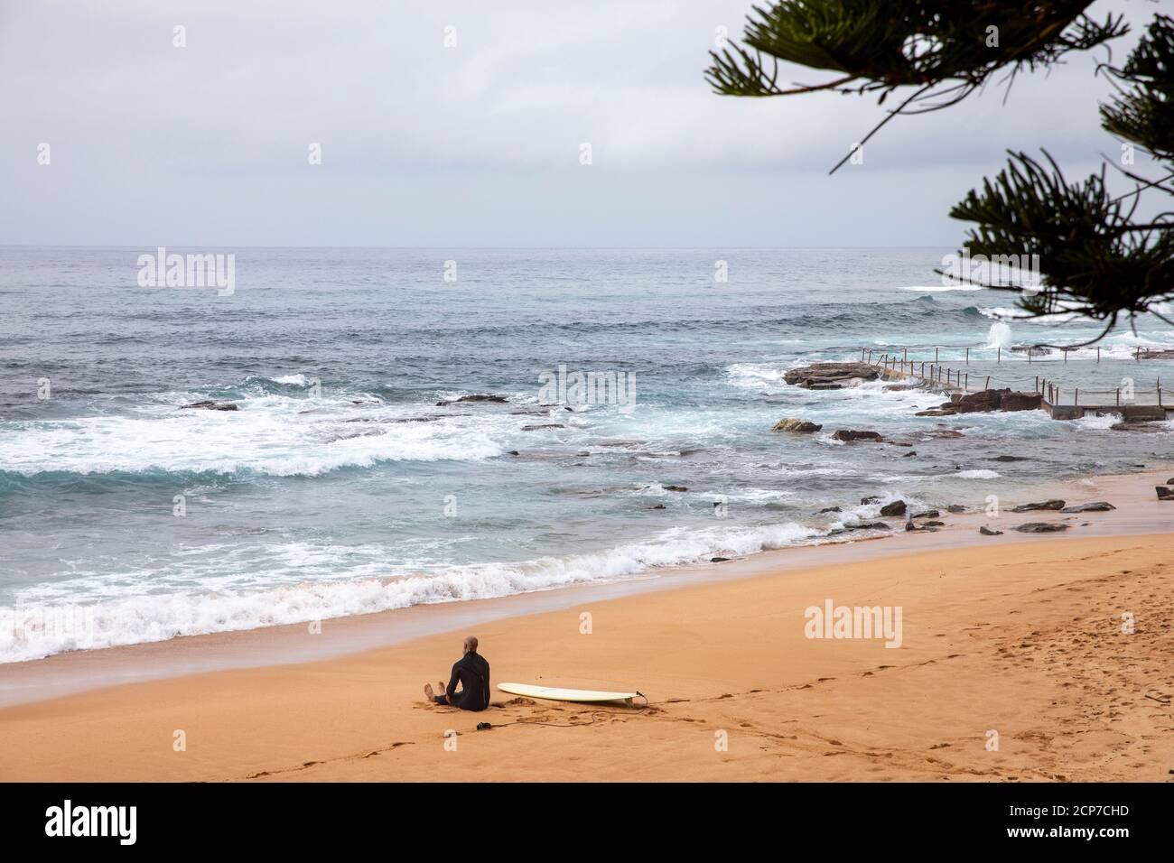Il surfista maschile su una spiaggia di Sydney si esercita e si allunga prima Verso un surf nell'oceano, Sydney, NSW, Australia Foto Stock