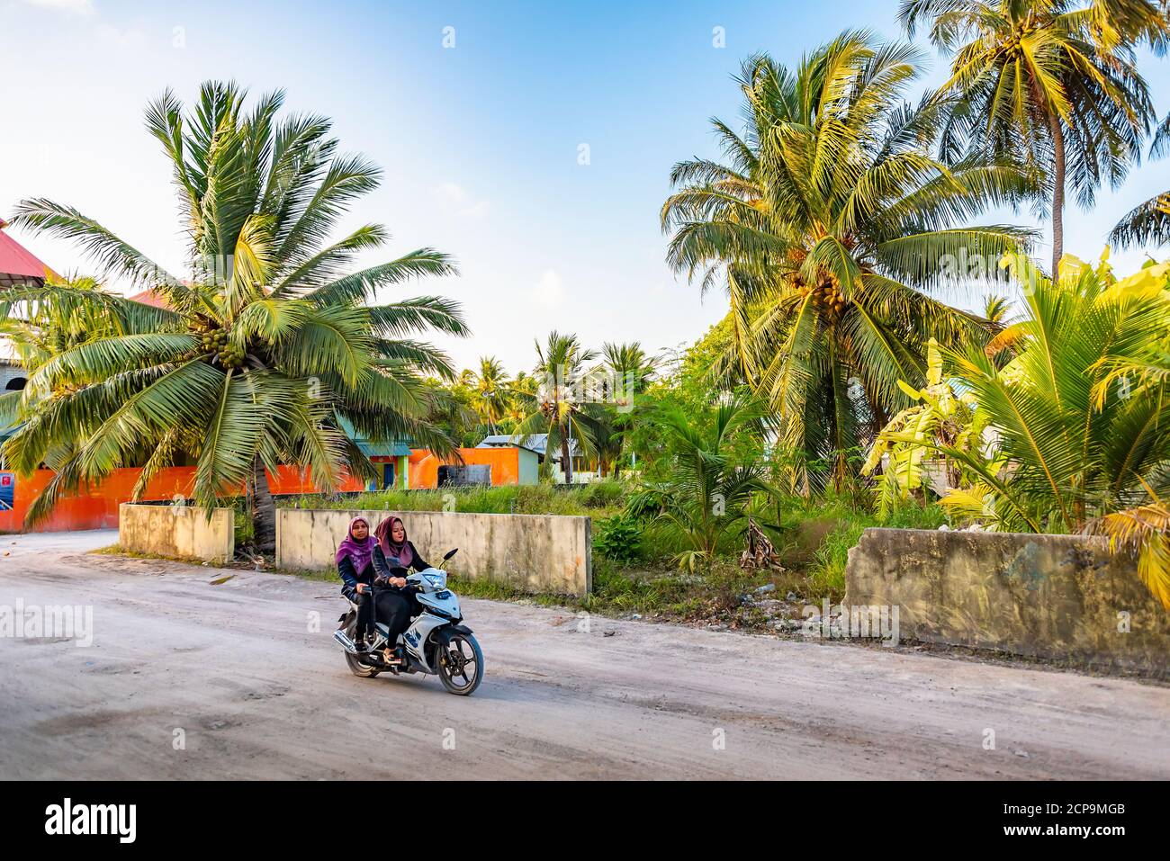 FULAHMULAH, MALDIVE - 9 APRILE, 2017: Due donne in abbigliamento musulmano  cavalcano un ciclomotore sull'isola equatoriale Fulahmulah, Maldive,  nell'oceano indiano Foto stock - Alamy