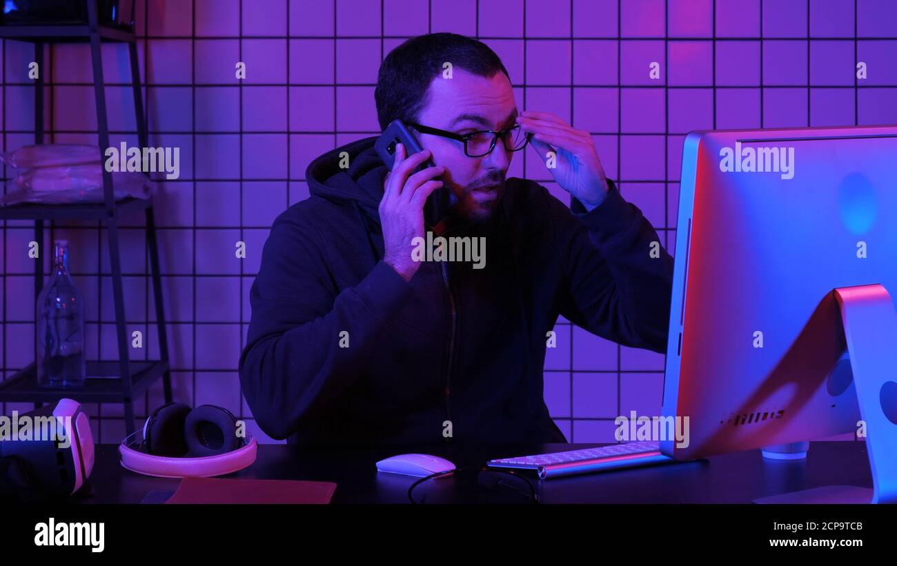 Specialista di codifica in casual con il computer e parlare per telefono w Foto Stock