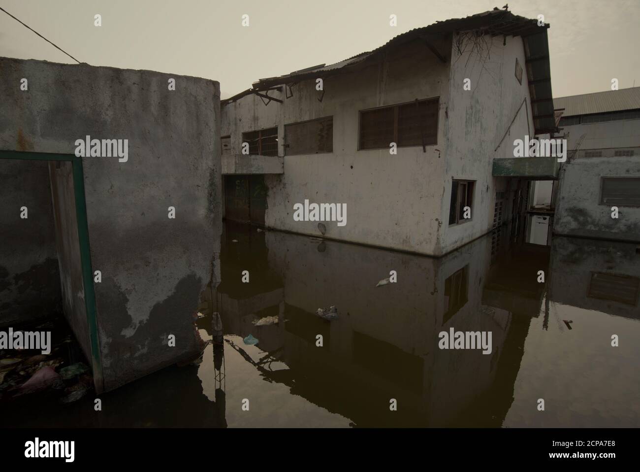 Edifici di magazzino sommersi su un'area costiera che soffre di cedimenti di terra e inondazioni di acqua di mare. Foto Stock