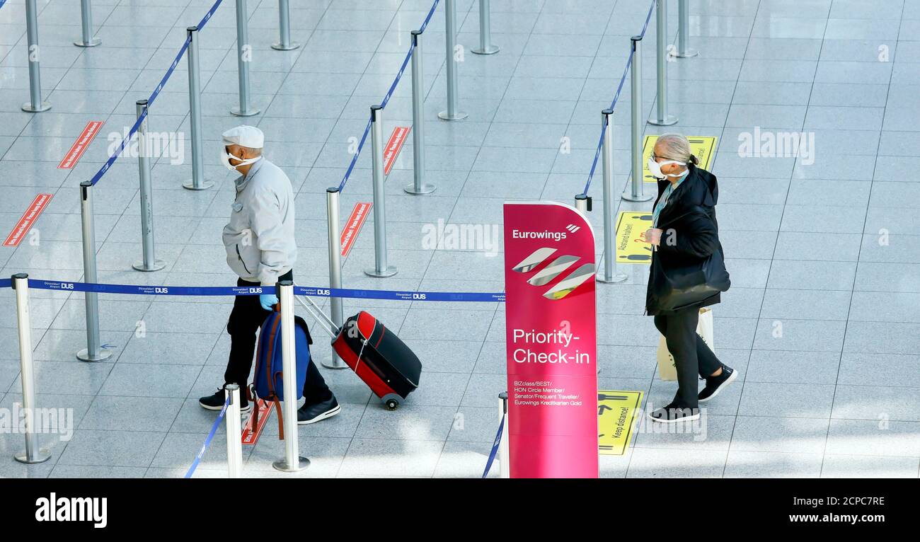 Passeggeri con maschere facciali presso il banco di check-in Eurowings dell'aeroporto di Düsseldorf in occasione della pandemia della corona, Duesseldorf, Nord Foto Stock