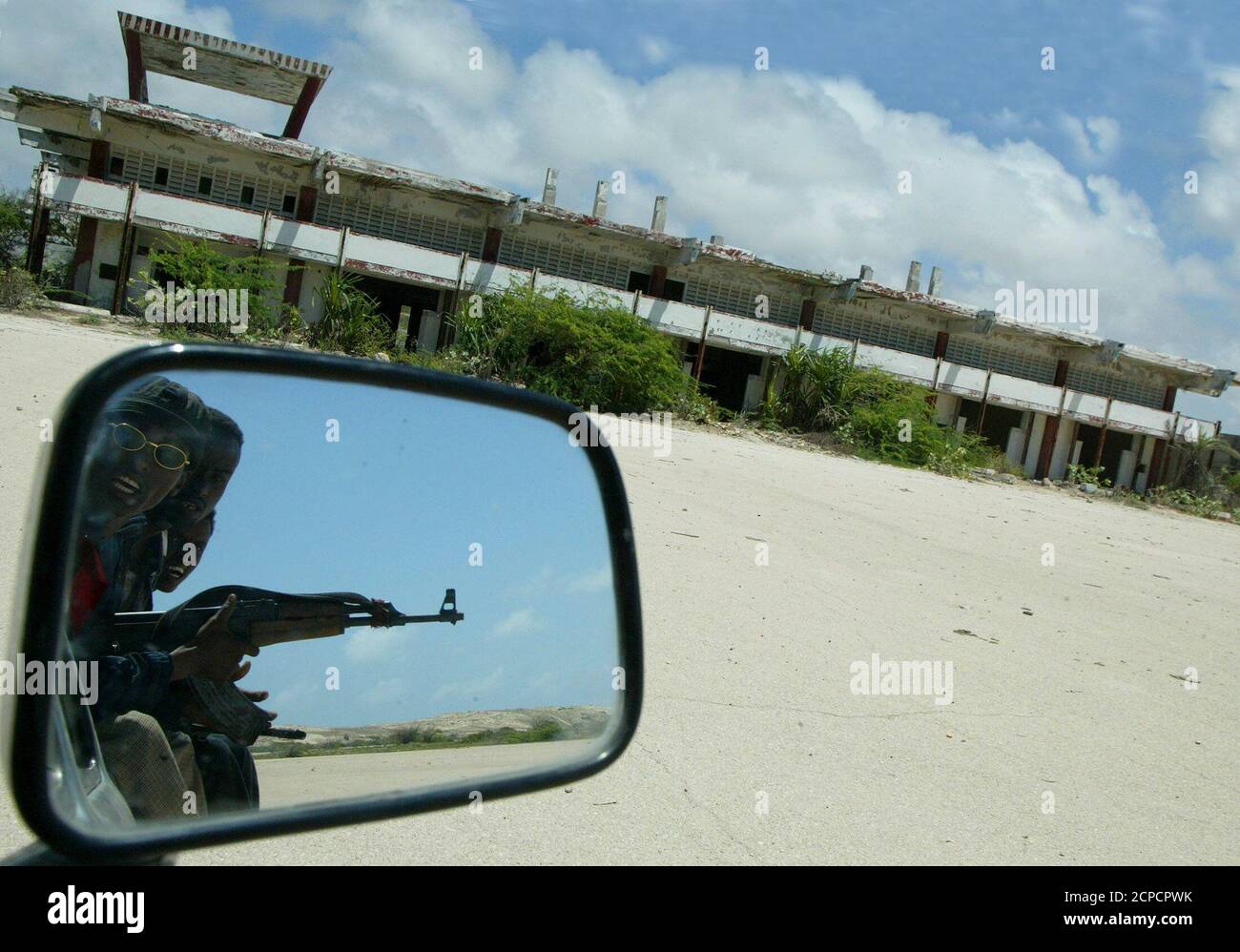 I gunmen somali guidano sulla pista dell'aeroporto internazionale di Mogadiscio che è stato distrutto durante i combattimenti tra le fazioni somale rivali dopo il rovesciamento del dittatore Mohammed Siad barre nel 1991. Le parti di motore carred surcresciute dai cactus sono tutte che rimangono oggi di due elicotteri neri del Hawk degli Stati Uniti abbattuti dai gunmen somali un decennio fa. Le looter sono state rapide per trasformare il telaio in alluminio in utensili domestici. Foto scattata il 24 settembre 2003. PER ANDARE CON SOMALIA BLACKHAWKDOWN REUTERS/ANTONY NJUGUNA Foto Stock