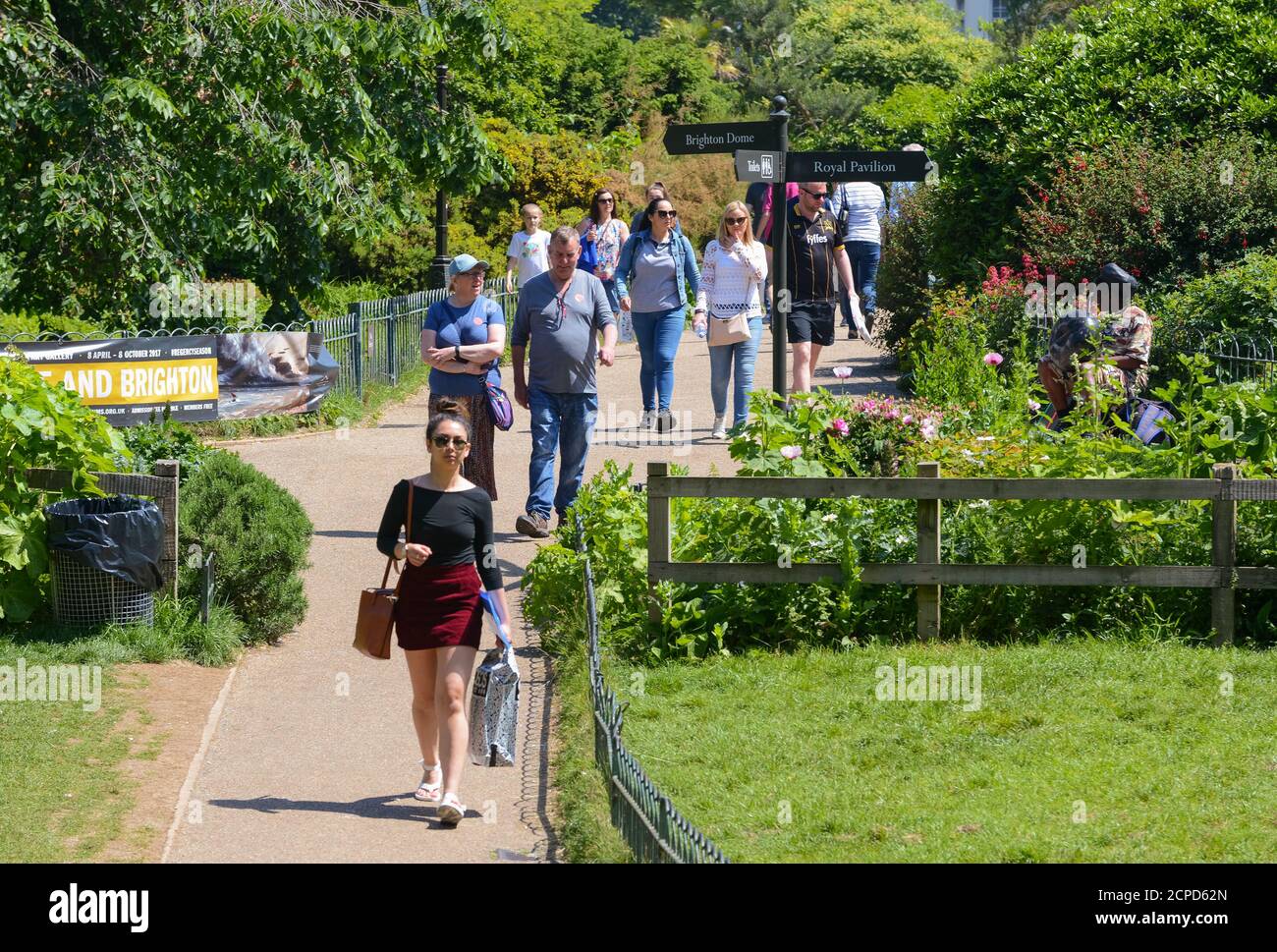 Folle di persone che camminano attraverso il parco presso i Royal Pavilion Gardens in una calda giornata estiva a Brighton, East Sussex, Inghilterra, Regno Unito. Foto Stock