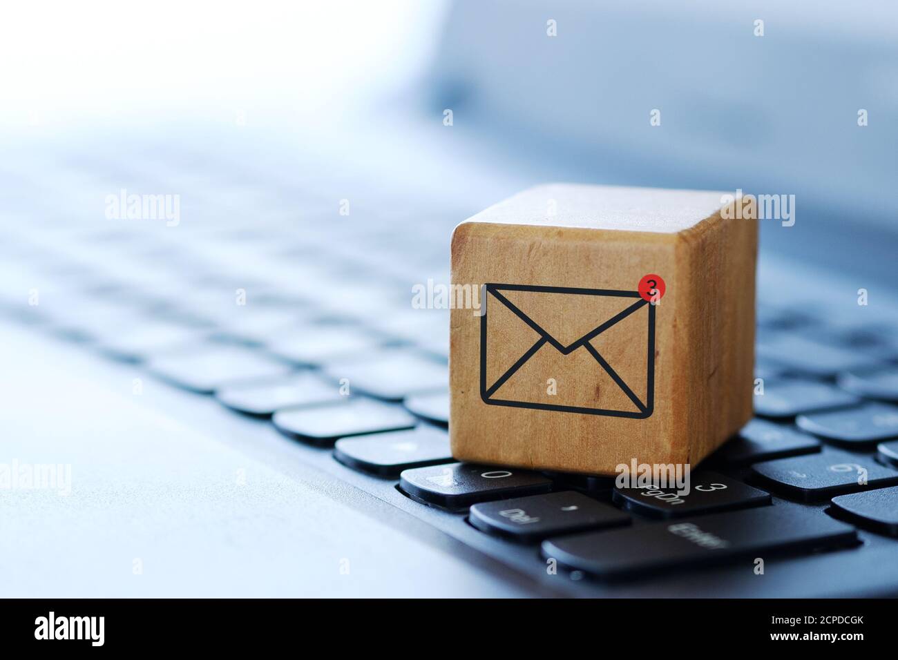 Un simbolo di inviluppo su un cubo di legno sulla tastiera di un computer, con uno sfondo sfocato e una profondità di campo poco profonda. Foto Stock