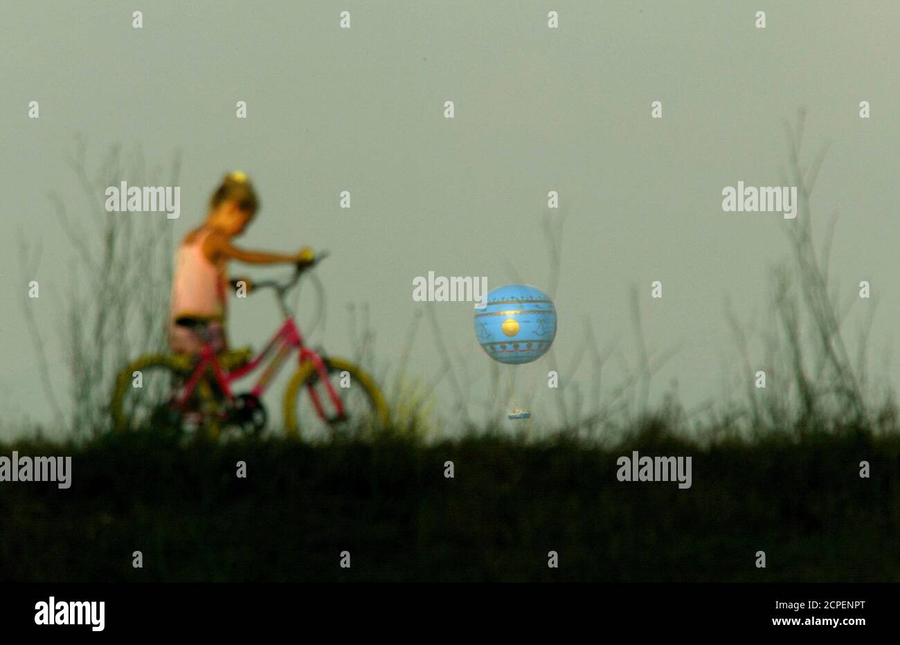 Una giovane ragazza cammina in bicicletta su una collina mentre una mongolfiera di elio vola sopra lo skyline di Roma alla pausa di giorno 28 luglio 2003. La mongolfiera, che era tutta impostata per diventare l'ultima attrazione turistica della città, ha avuto un problema piuttosto insolito - troppo aria calda. La mongolfiera può volare solo all'alba e al tramonto, poiché le correnti termali generate dalle alte temperature di mezzogiorno si fermano ai turisti godendo di una vista aerea dell'eterna città a pranzo. REUTERS/Alessandro Bianchi REUTERS DJM/WS Foto Stock