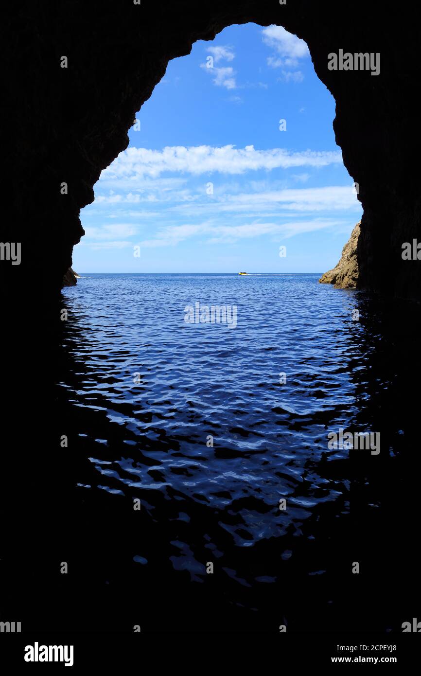 La vista dall'interno della Grotta del Mare di Orua sulla Penisola di Coromandel, Nuova Zelanda, che guarda all'oceano. Un tour in barca è appena visibile sull'acqua Foto Stock