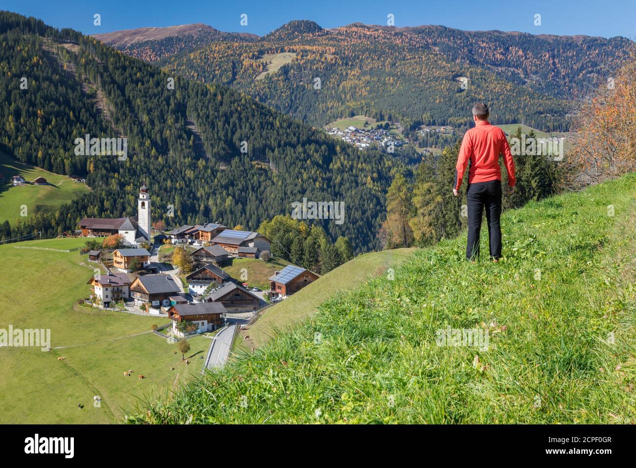 Uomo che si affaccia dall'alto sul villaggio di Corte / Curt nella valle di Marebbe / Enneberg, Bolzano, Alto Adige, Südtirol, Italia Foto Stock