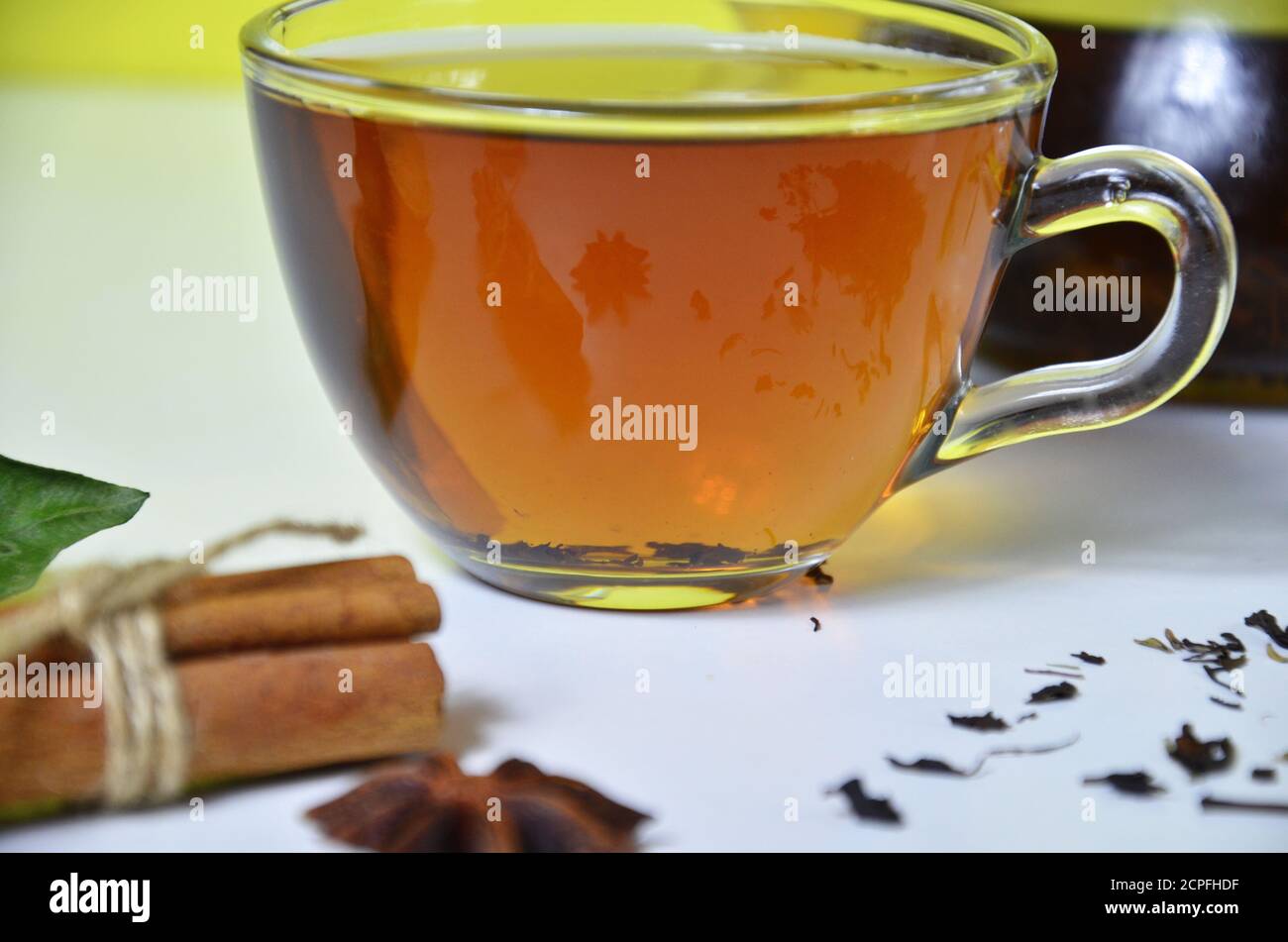 Tè in tazza di vetro con cannella e anice su sfondo bianco. Foto Stock