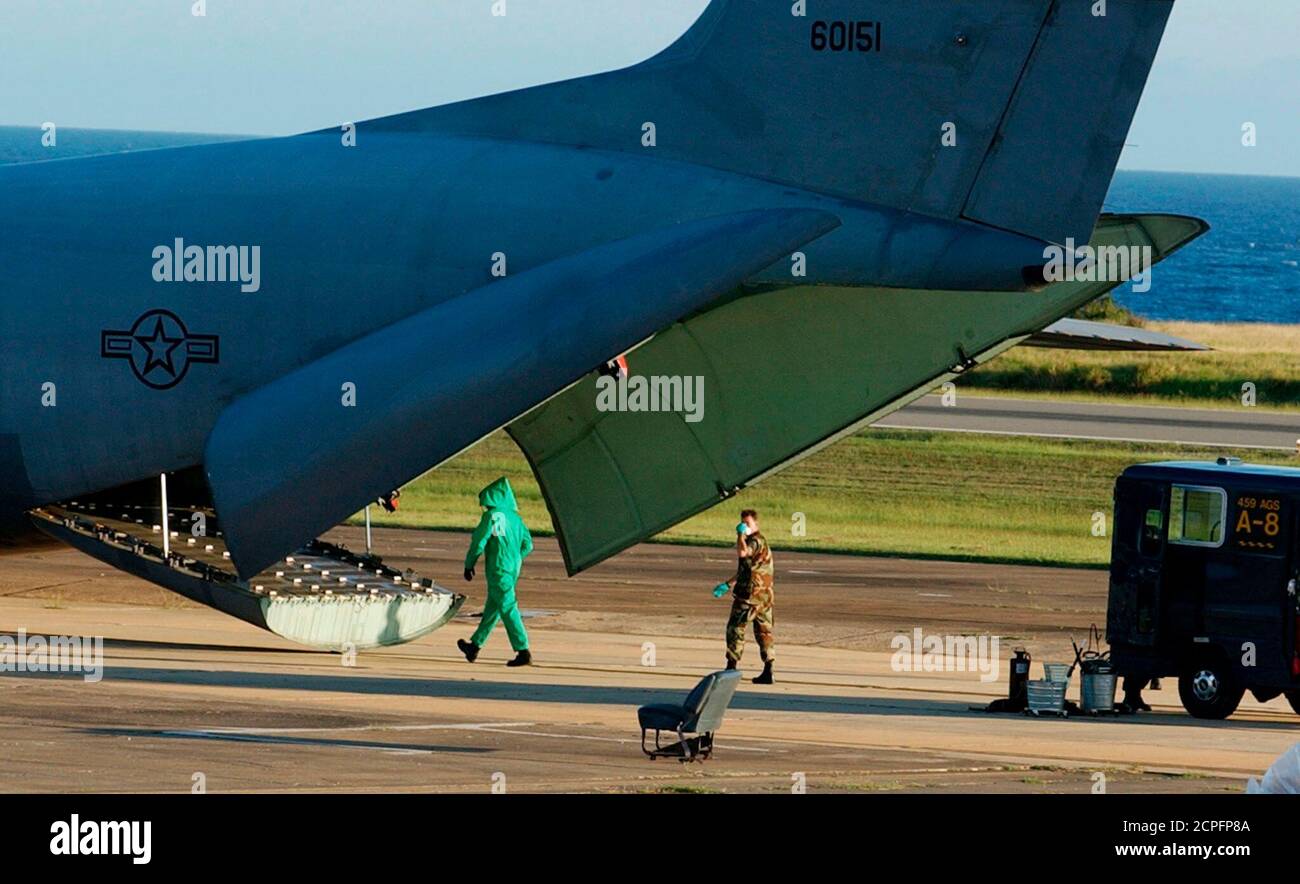 I membri non identificati della squadra di decontaminazione militare in  abbigliamento protettivo entrano in un aereo della US Air Force C-141 dopo  che è arrivato alla base navale degli Stati Uniti nella