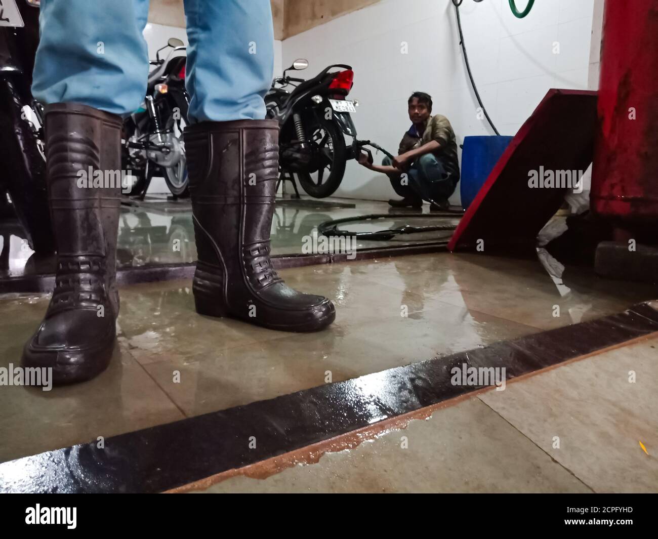 DISTRETTO KATNI, INDIA - 18 GENNAIO 2020: Scarpe di sicurezza uomo ingegnere automobilistico indiano primo piano su pavimento di lavaggio presso l'officina di moto Hero. Foto Stock