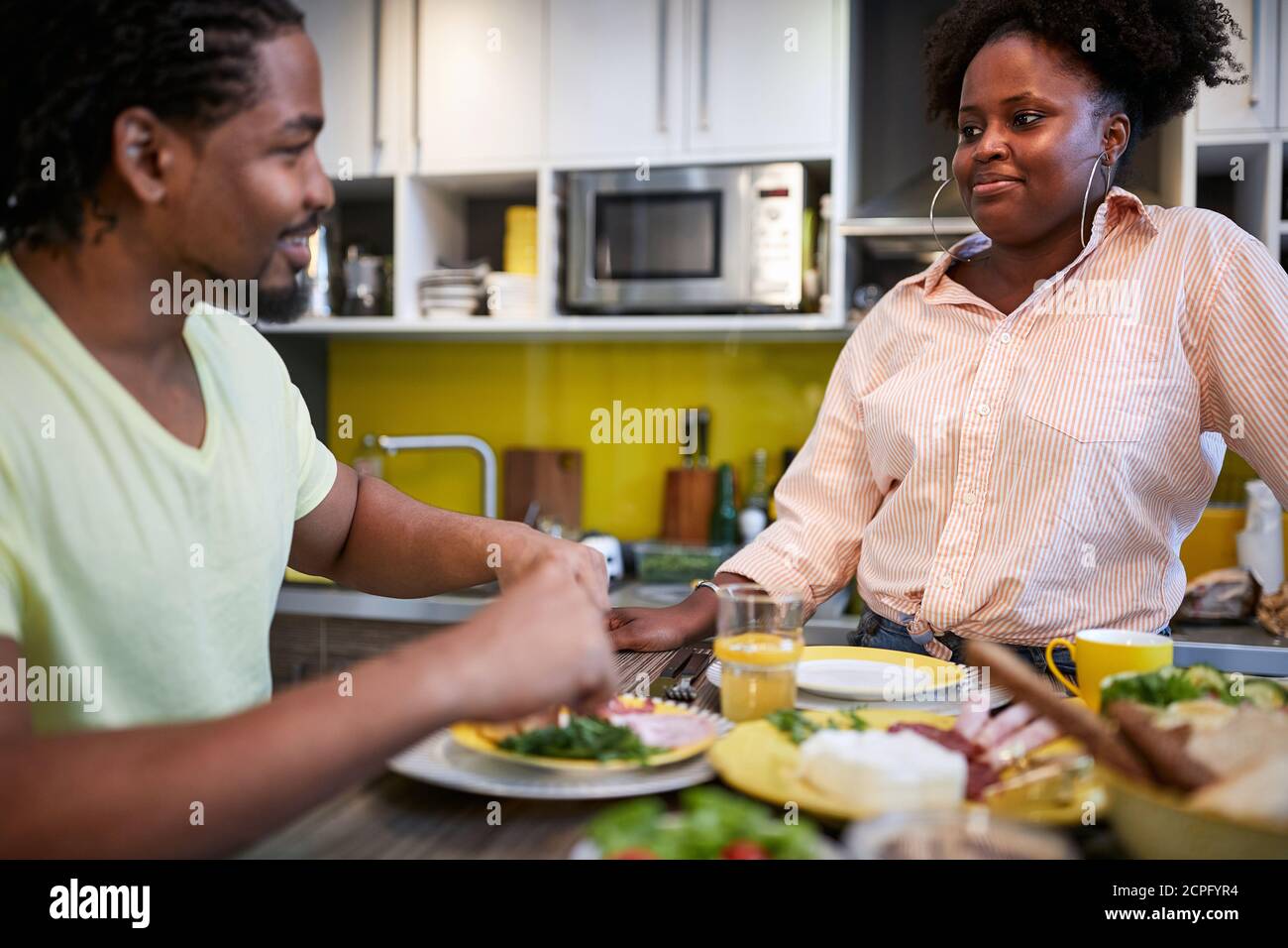 Marito e moglie africani in cucina a mangiare Foto Stock